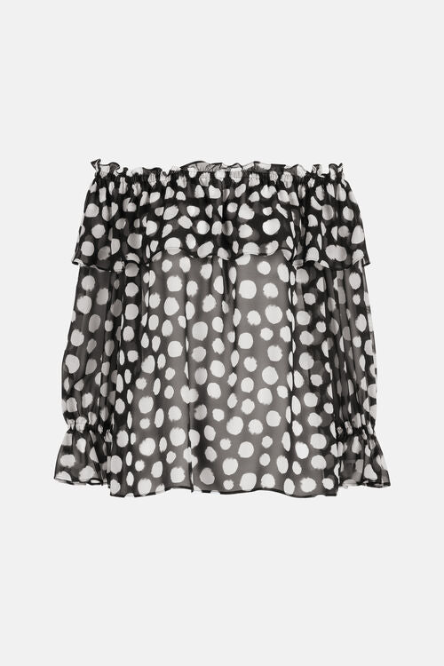 Black sheer off-shoulder blouse with white irregular polka dots. Features a ruffled, elasticized neckline, a ruffled tier, an
