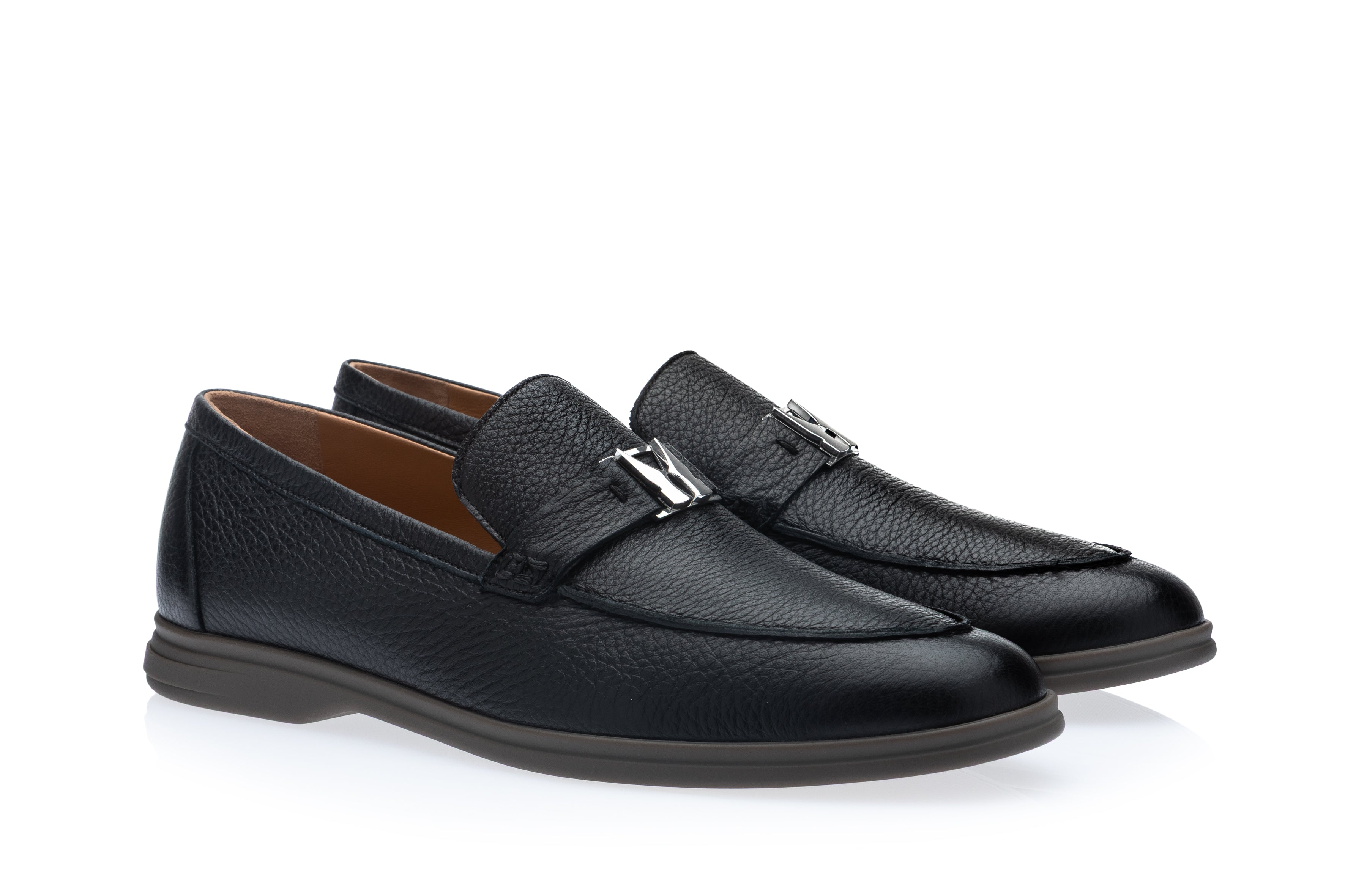 Navy blue pebbled leather loafers with moc-toe stitching, silver-toned M-shaped buckles, and dark grey soles.