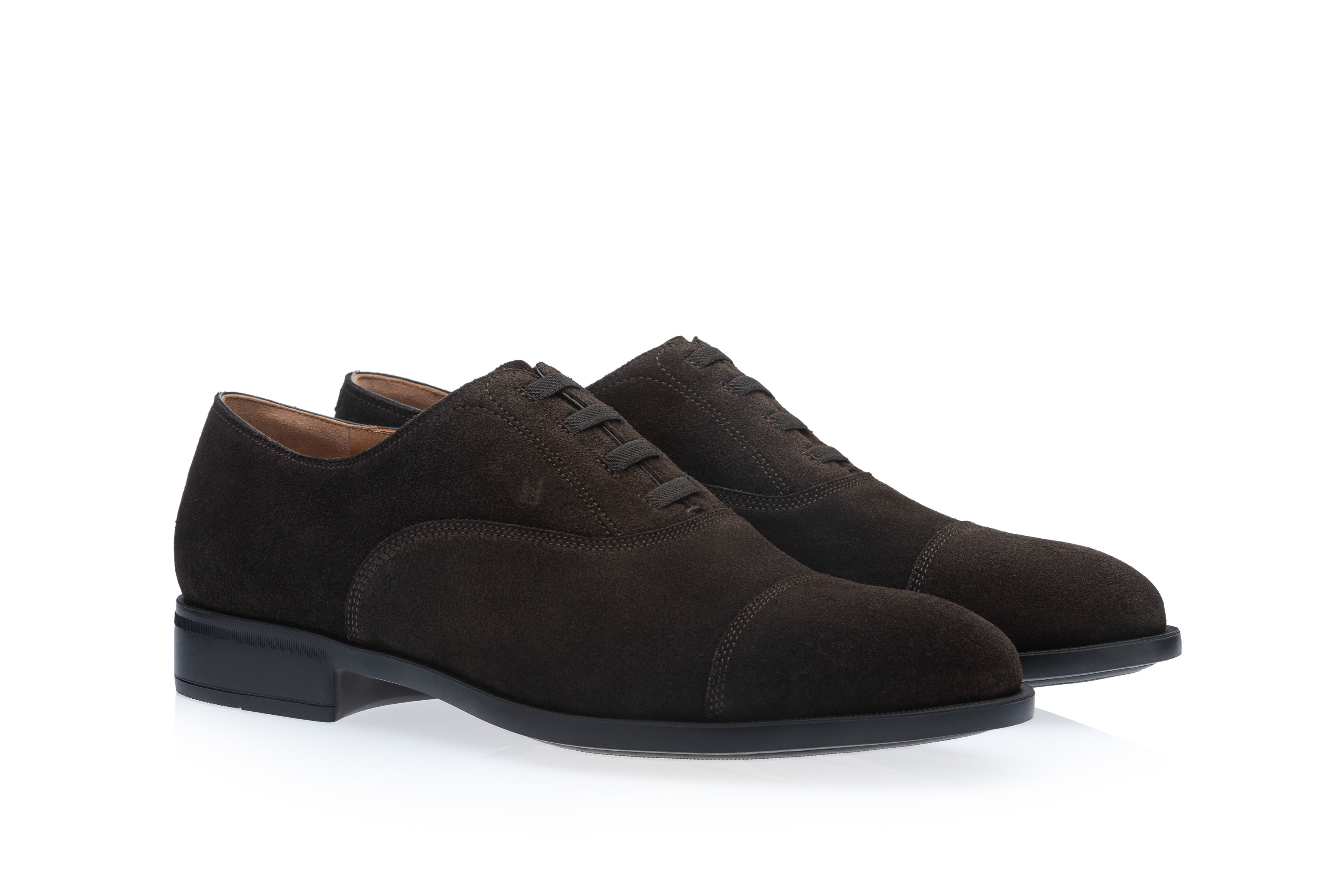 Pair of dark brown suede Oxford shoes with cap toes, closed lacing, and black soles with low heels.