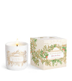 White ceramic candle with lit wick and gold-toned floral design. Matching light beige box features a green holly and red berr