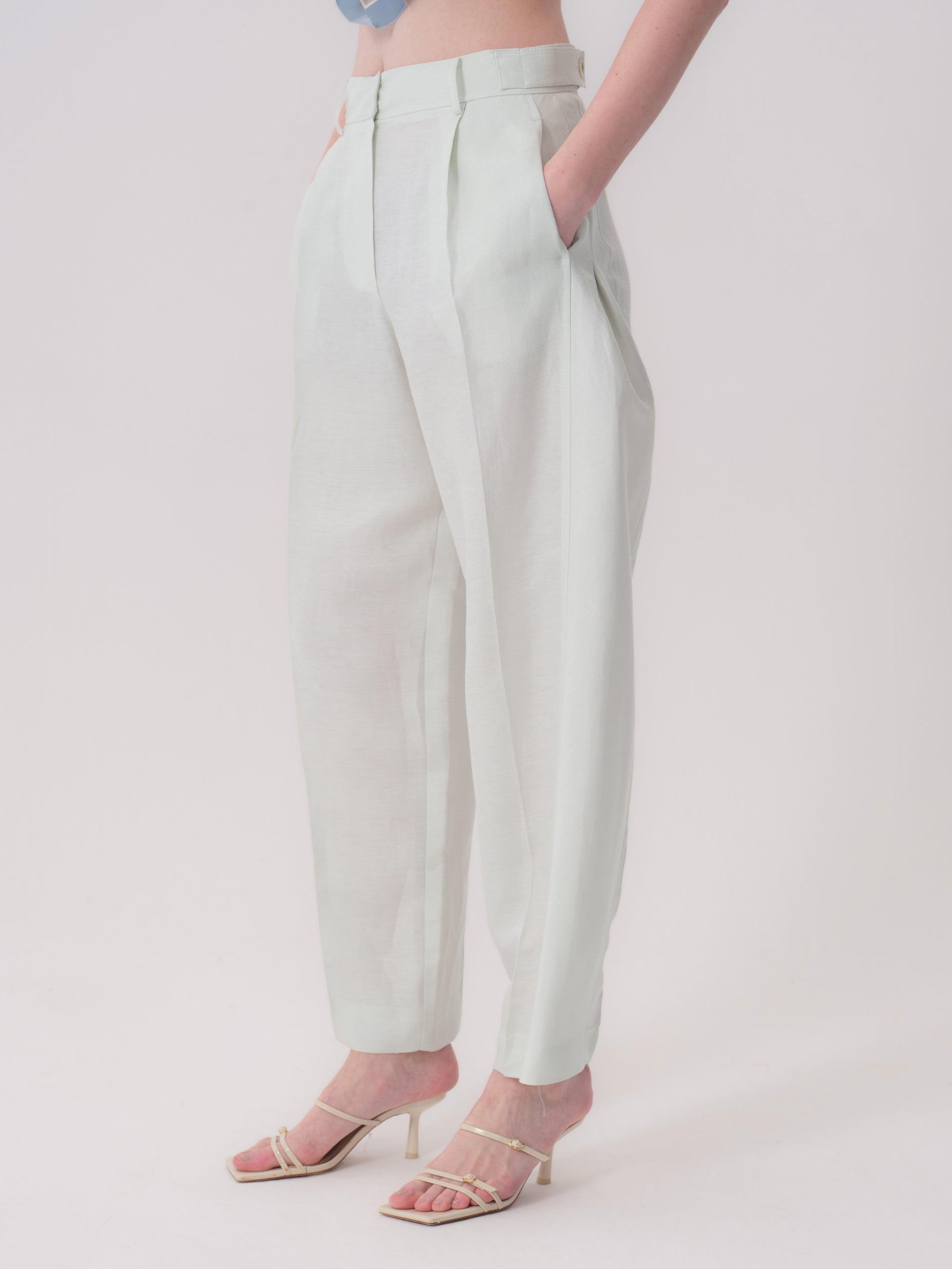 Light mint green, high-waisted, wide-leg trousers with front pleats, belt loops, and side pockets, made from a lightweight fa