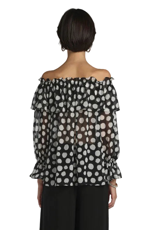 Sheer black off-shoulder blouse with white polka dots, ruffled elasticized neckline, tiered ruffle overlay, and long sleeves