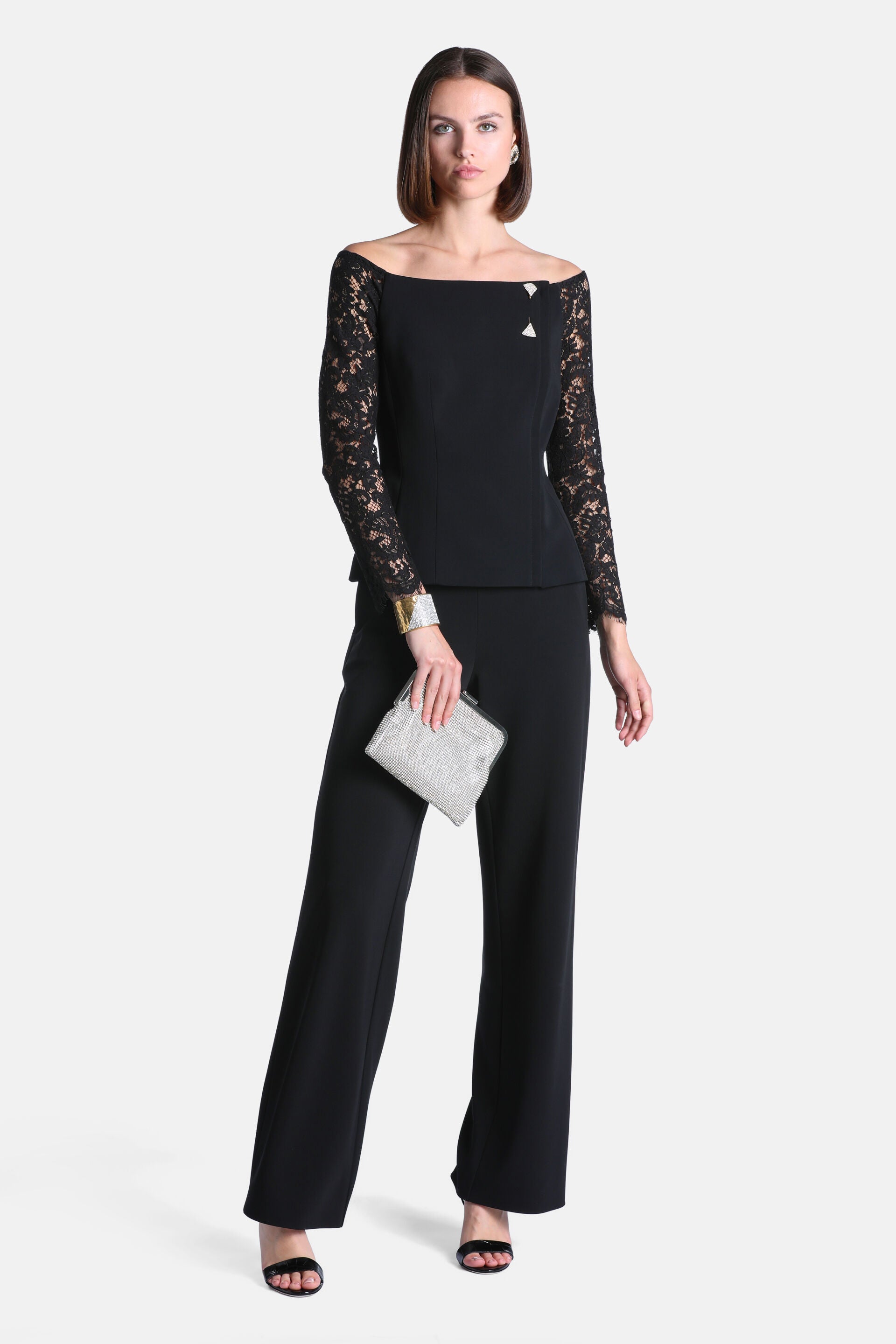 Black off-the-shoulder jacket with a smooth body, long lace sleeves, and a silver-toned triangular embellishment on the right