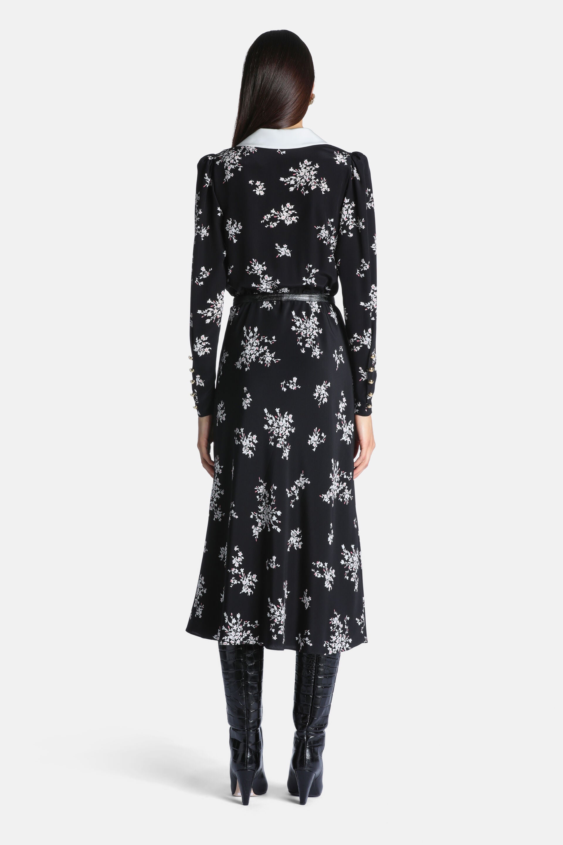 Black midi dress with white floral print, white collar, puffed shoulders, long sleeves with gold-toned cuff buttons, and a bl