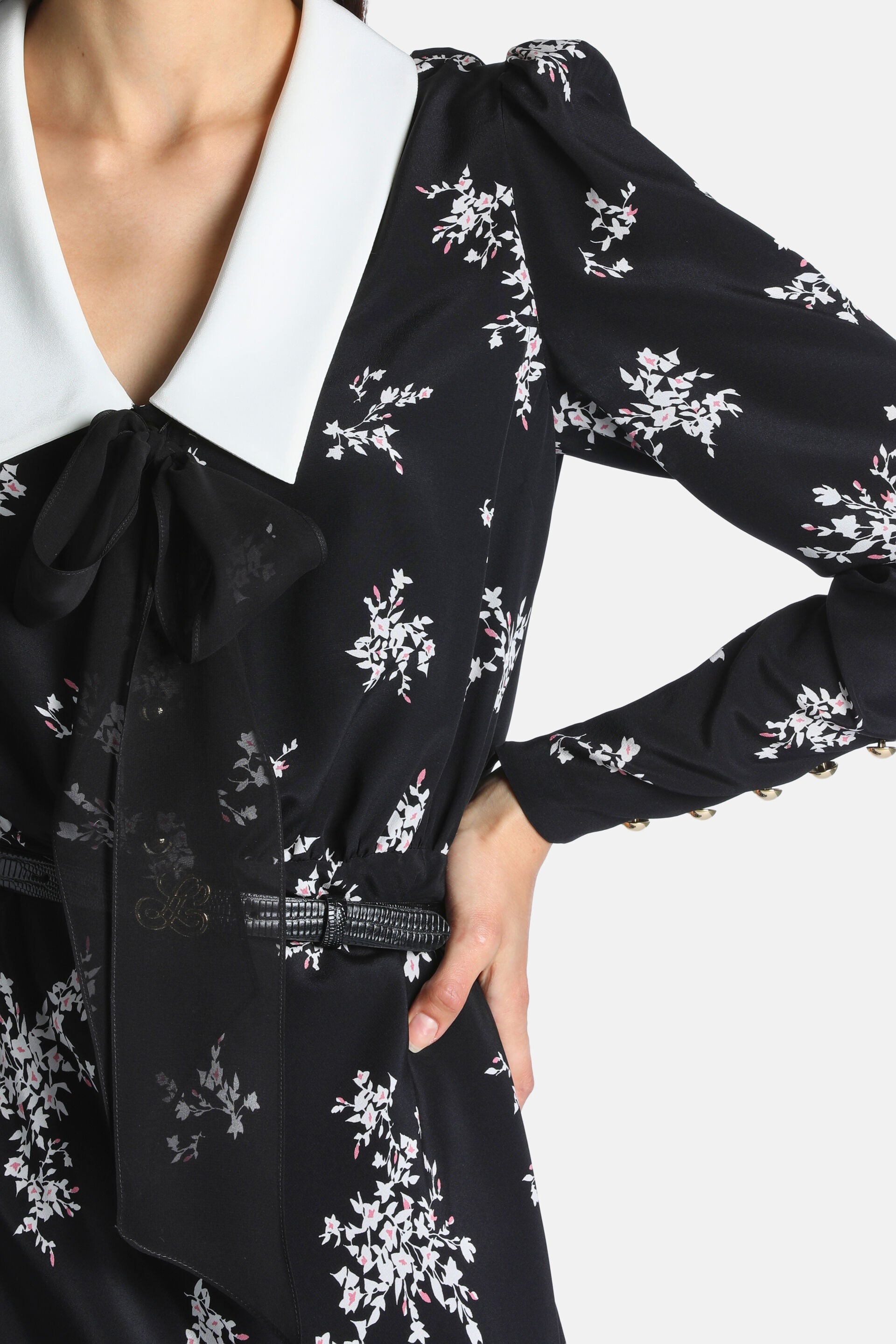 Black dress with white/pink floral print, white collar, black bow, puffed sleeves, gold-toned cuff buttons, and a black textu