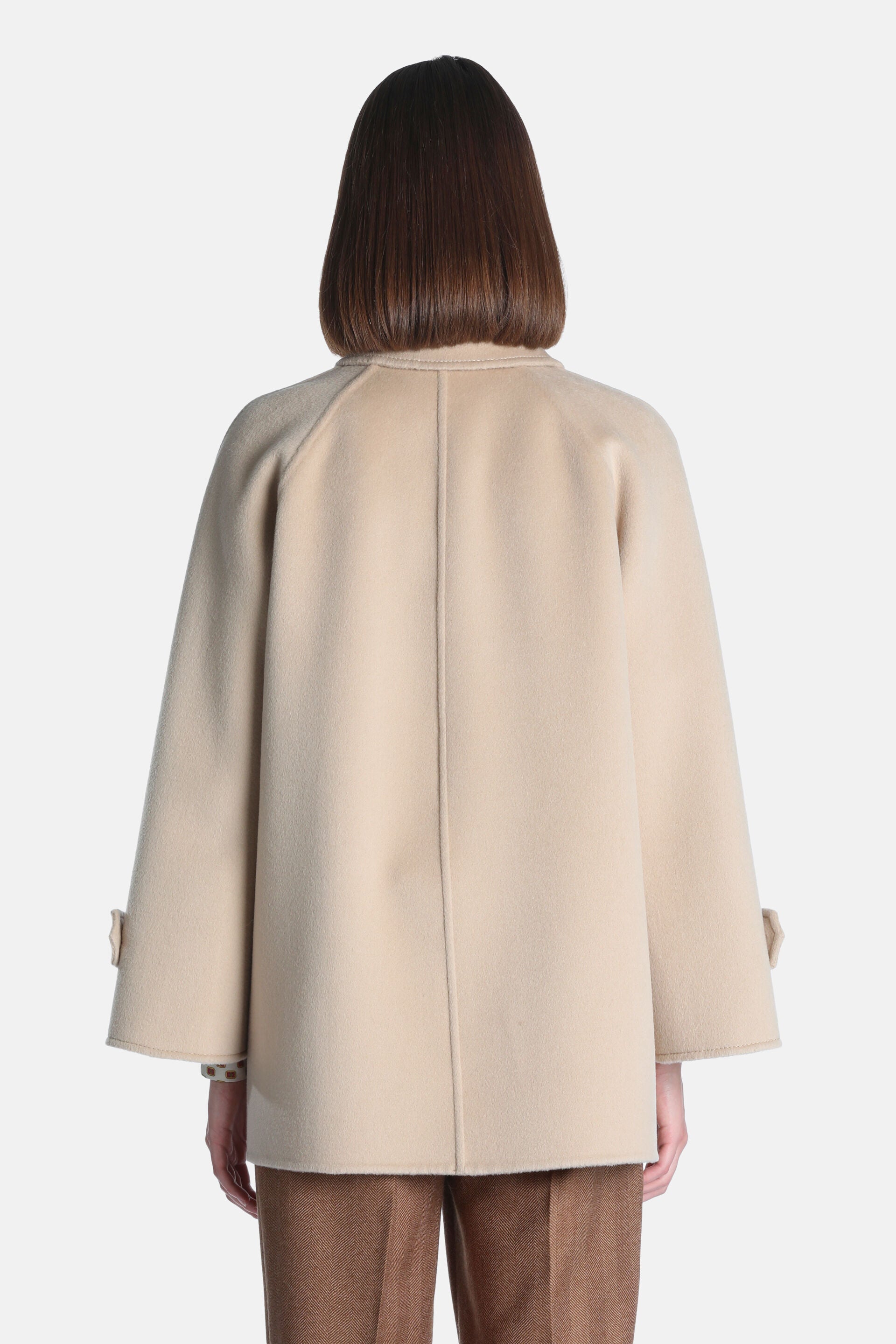 Beige short coat with wide raglan sleeves, buttoned tabs on cuffs, and a visible center back seam.