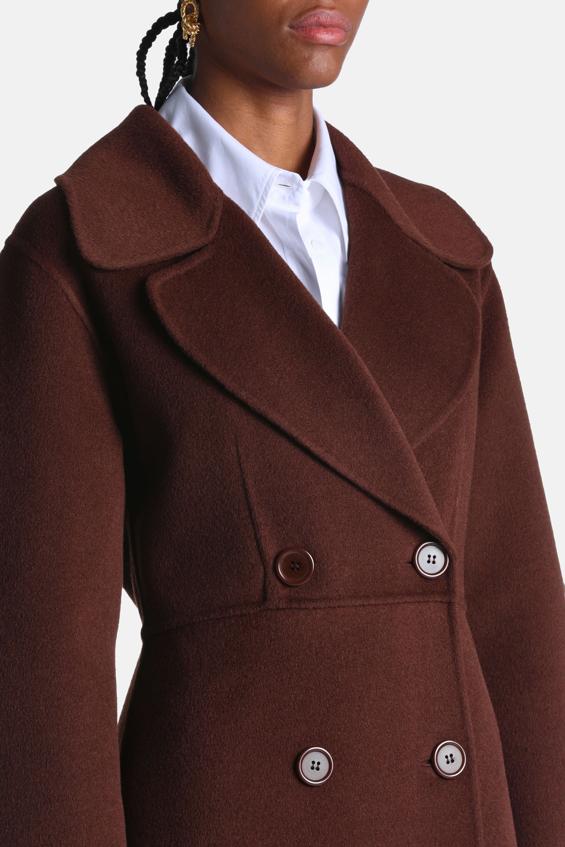Brown double-breasted coat with wide lapels, one dark brown button, and three light-colored buttons with dark centers.