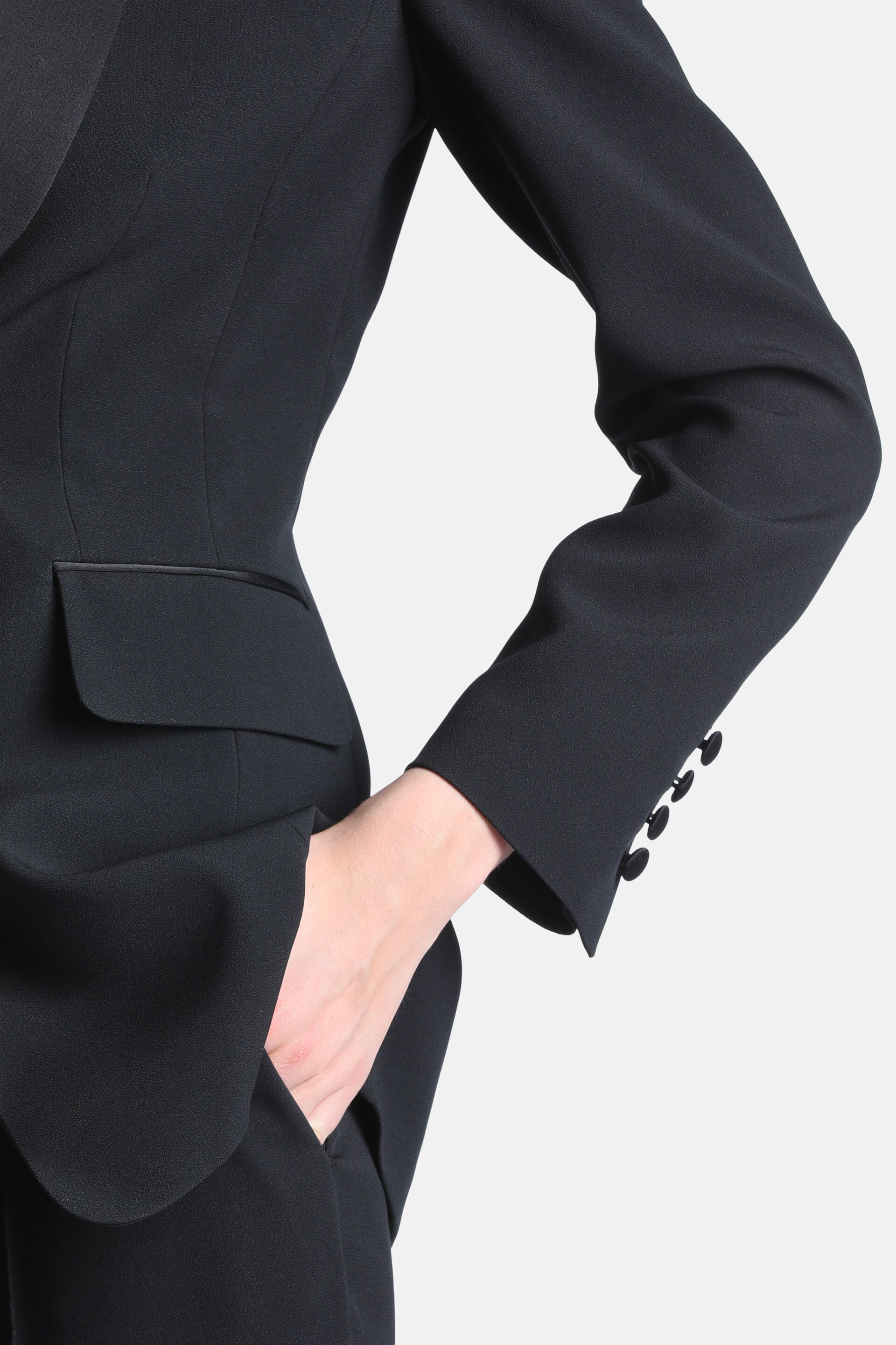 Black women's blazer, fitted, with a satin lapel, a flap pocket with satin trim, and a sleeve cuff with four black buttons.