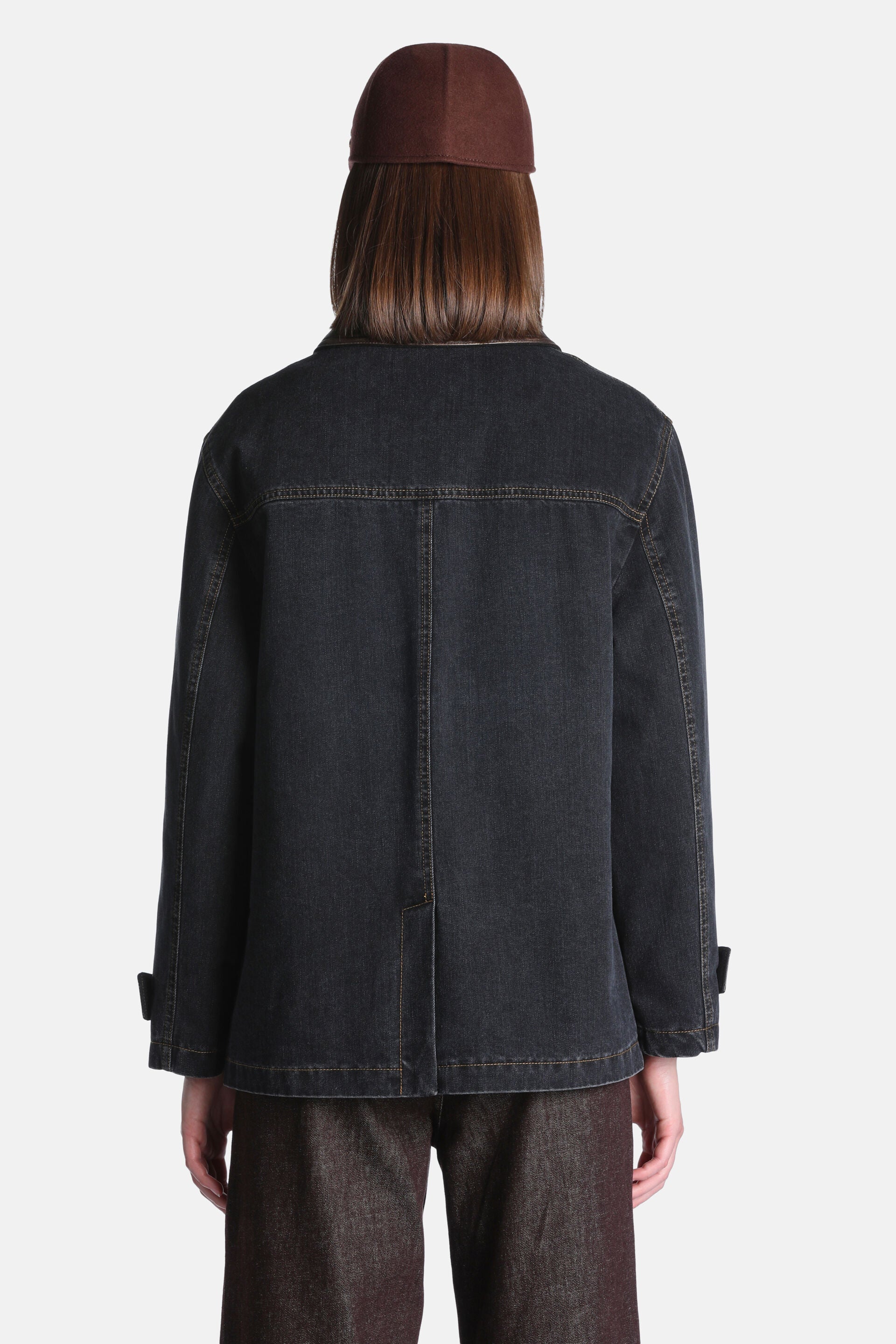 Dark black-brown denim coat with contrasting brown stitching, a back yoke, center back seam, and cuff tabs.