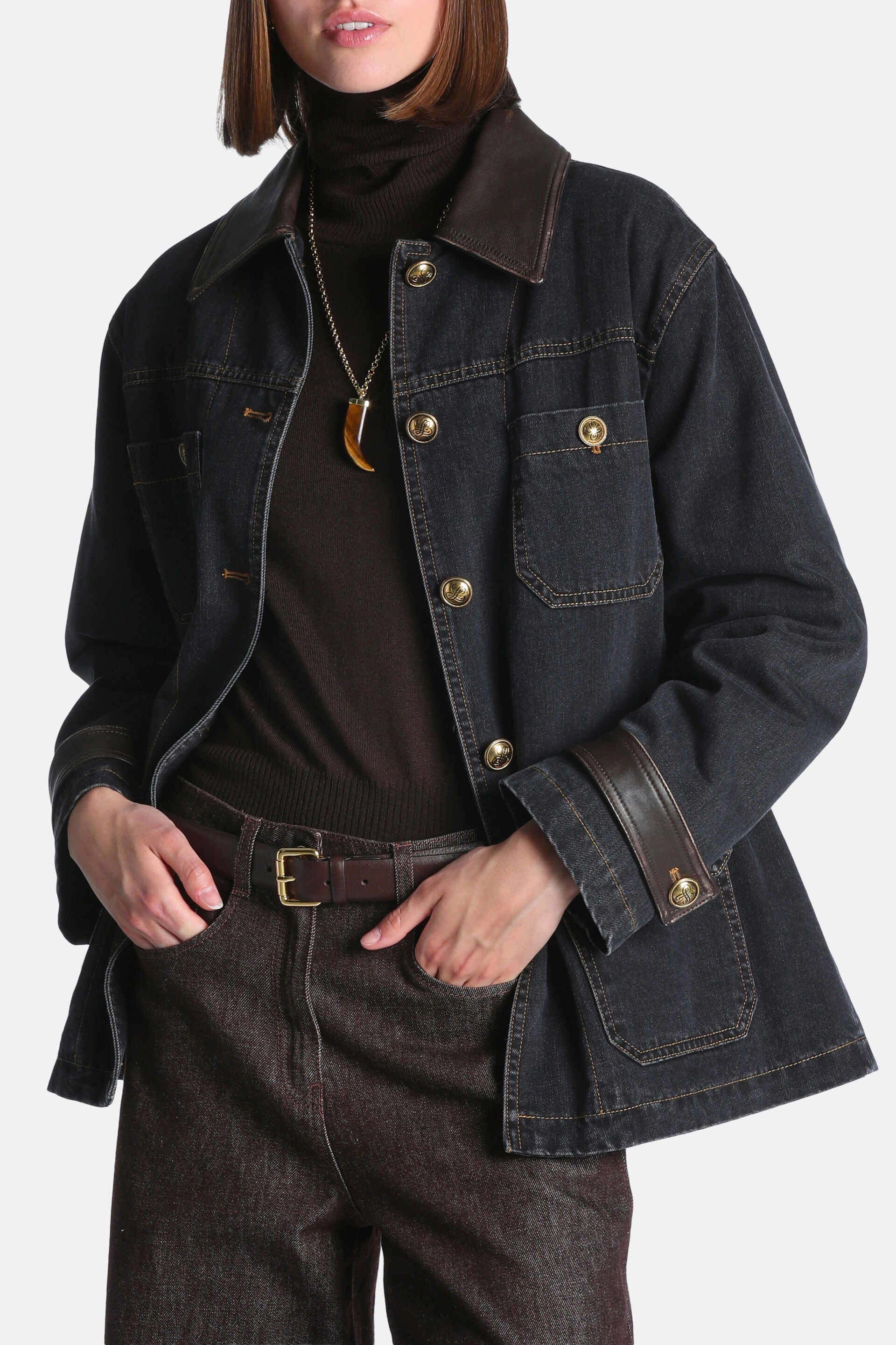 Black denim coat with brown leather-look collar and cuffs, gold-toned buttons, chest flap pockets, and lower patch pockets.
