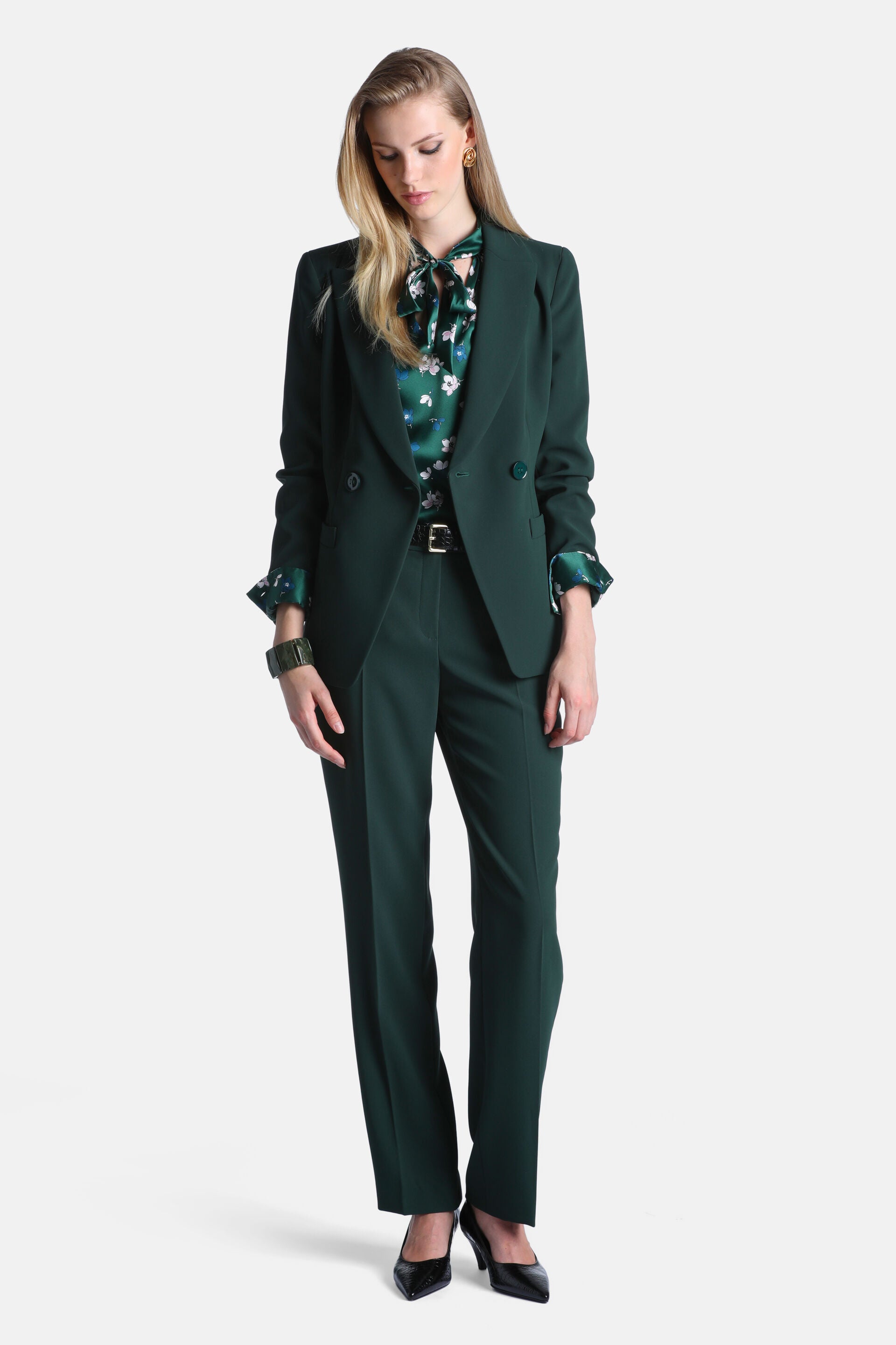 Dark green tailored trousers with a flat front, belt loops, and a prominent crease down each straight leg.