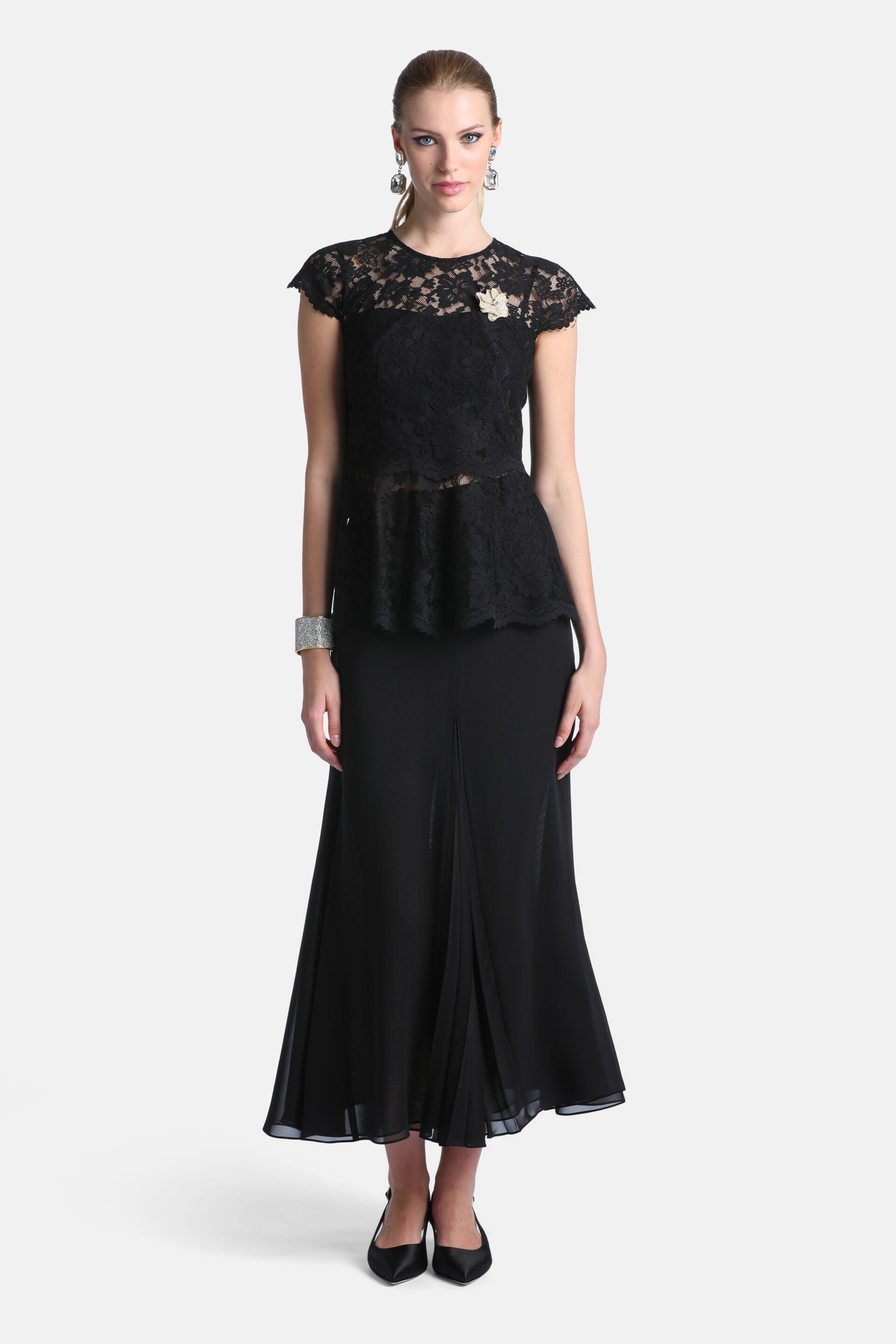 Black maxi skirt with a flowing A-line silhouette. Features a central front pleat detail and a slightly sheer hem.