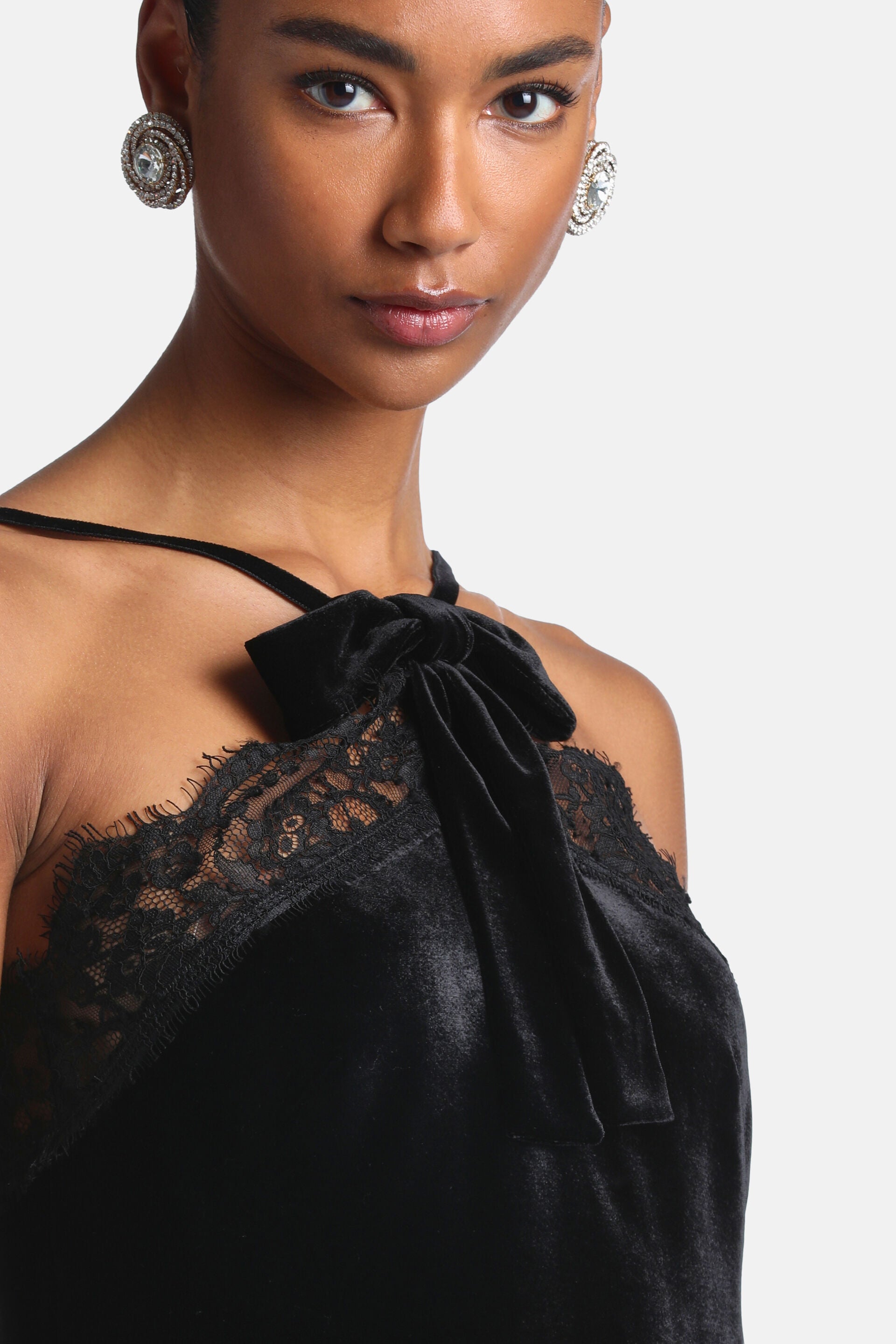 Black velvet top with a spaghetti strap, lace trim along the neckline, and a velvet bow tied at the right shoulder.