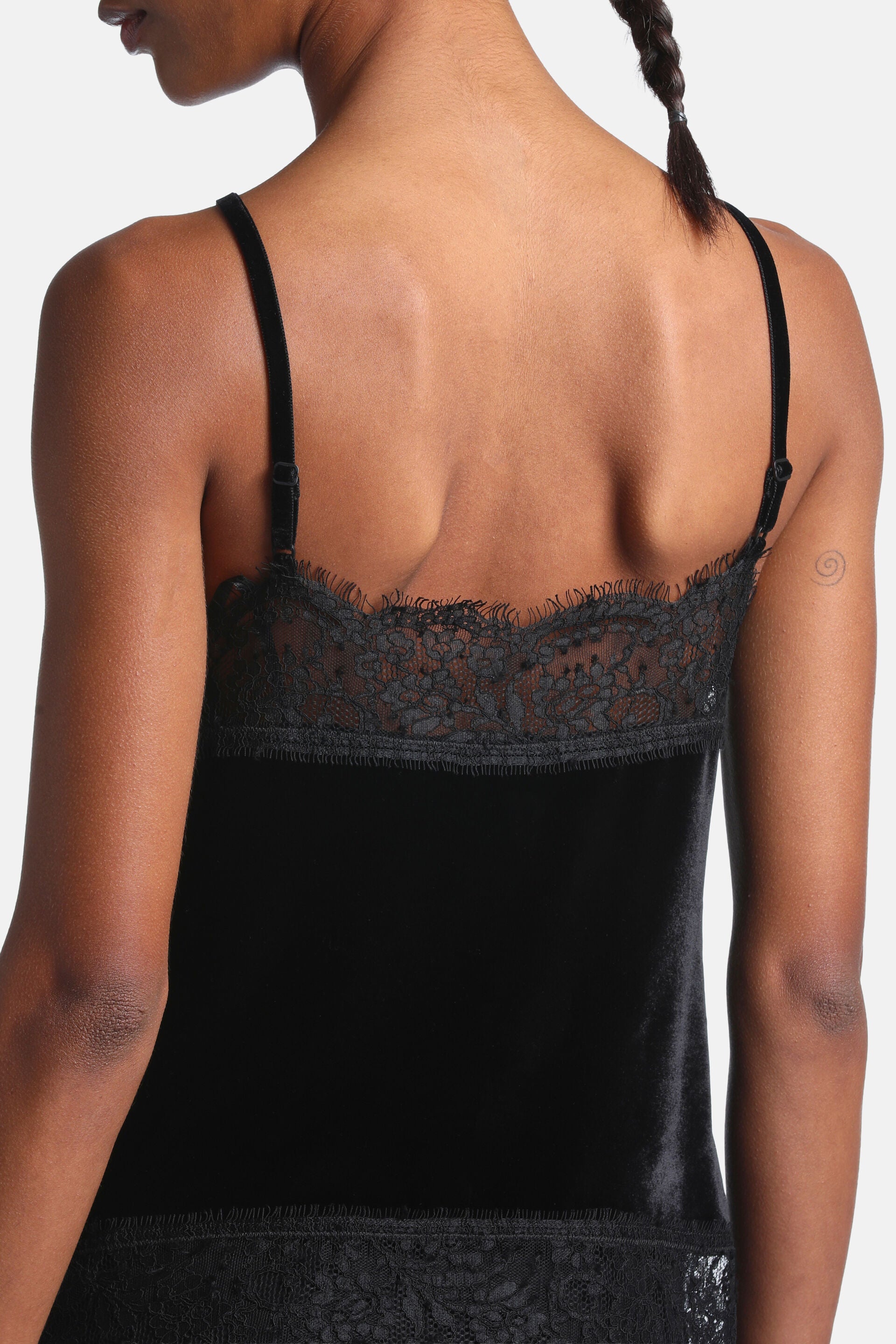 Black velvet cami top with adjustable spaghetti straps and black lace trim along the upper back and lower hem.