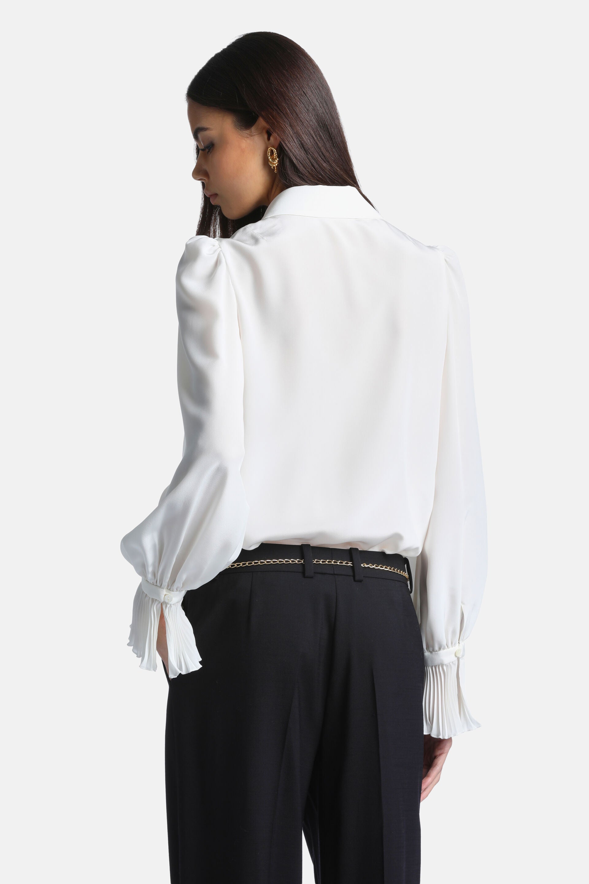 Ivory long-sleeved blouse with puffed shoulders, billowy sleeves, and wide pleated cuffs with button closures.