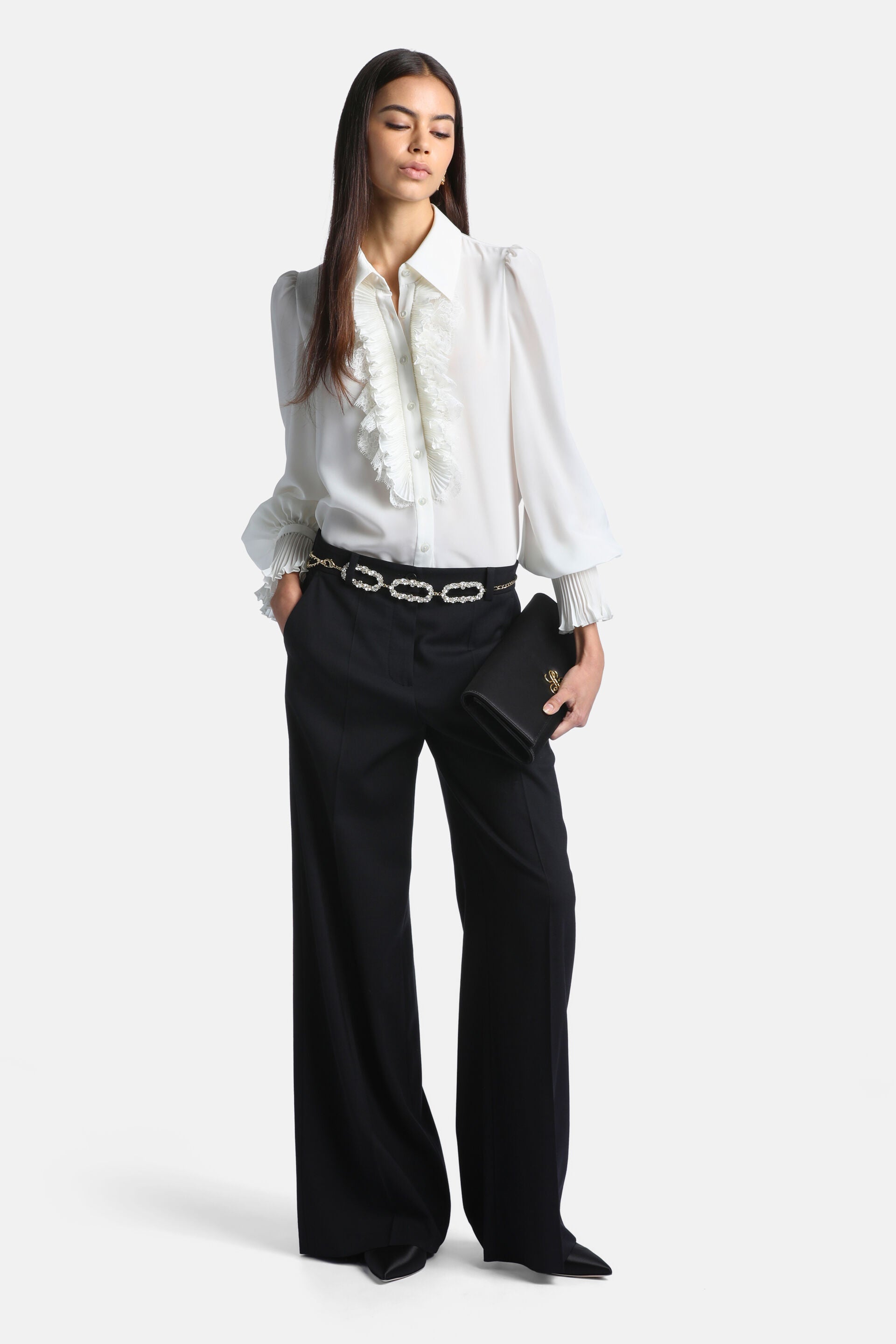 Ivory long-sleeved blouse with a pointed collar, ruffled placket with pearl-like buttons, puffed shoulders, and pleated cuffs