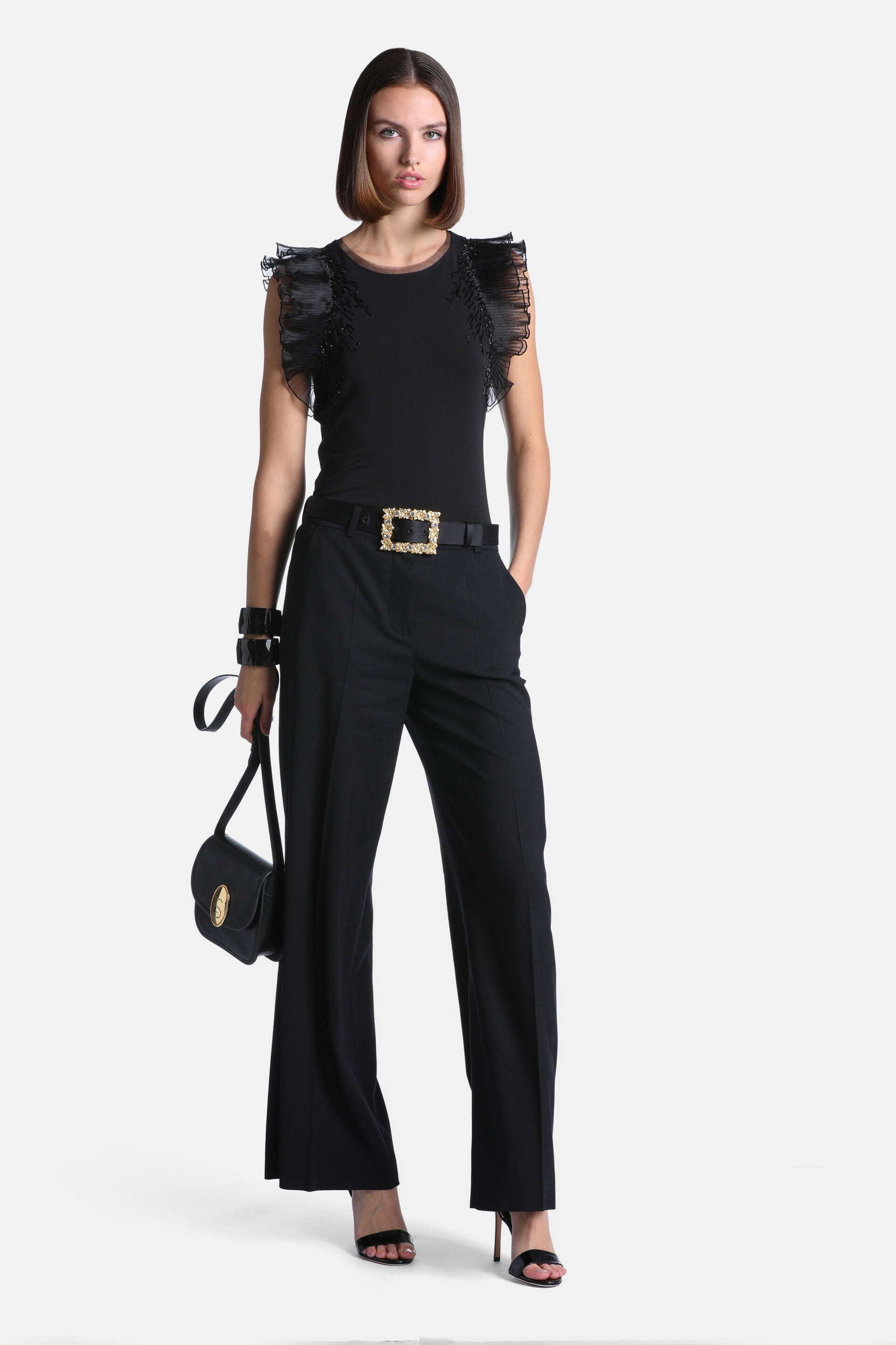 Black sleeveless top with a round neck and ruffled, sheer shoulder details embellished with small beads.