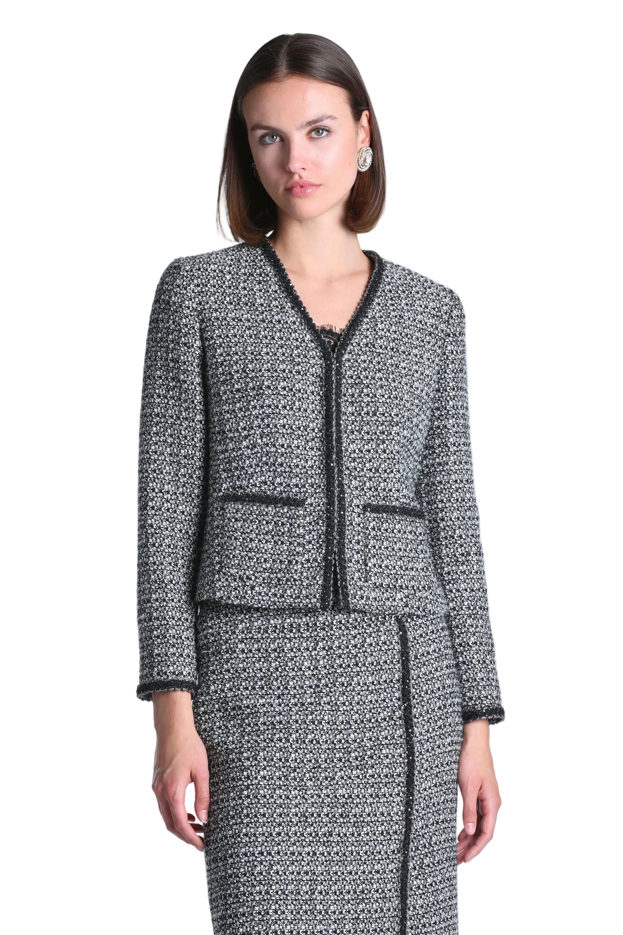 Black and cream tweed jacket with a V-neck, black trim along the neckline, front opening, two front pockets, and cuffs.