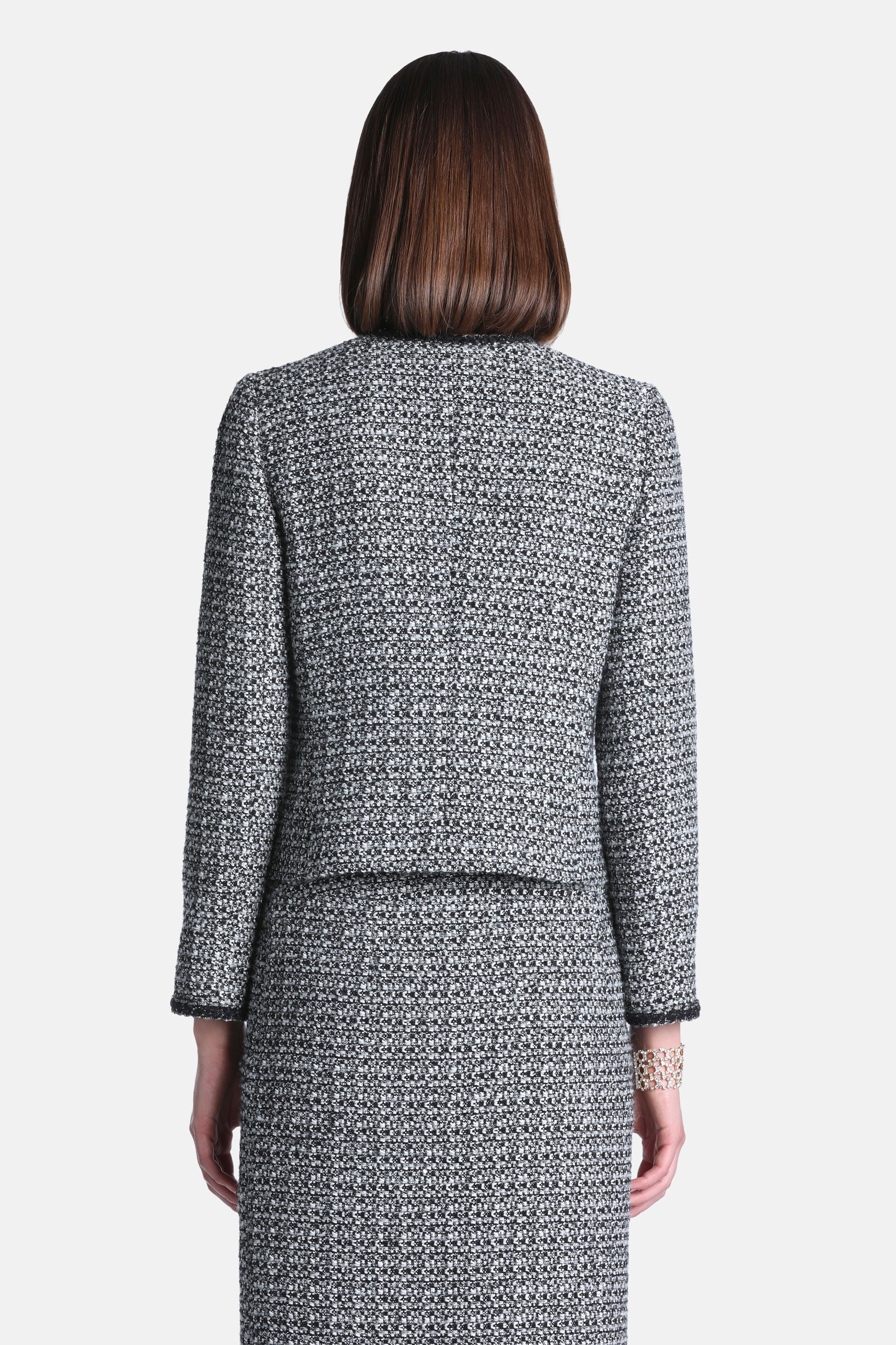 Black and cream tweed cropped jacket with a round neckline and black trim on the neckline and sleeve cuffs.