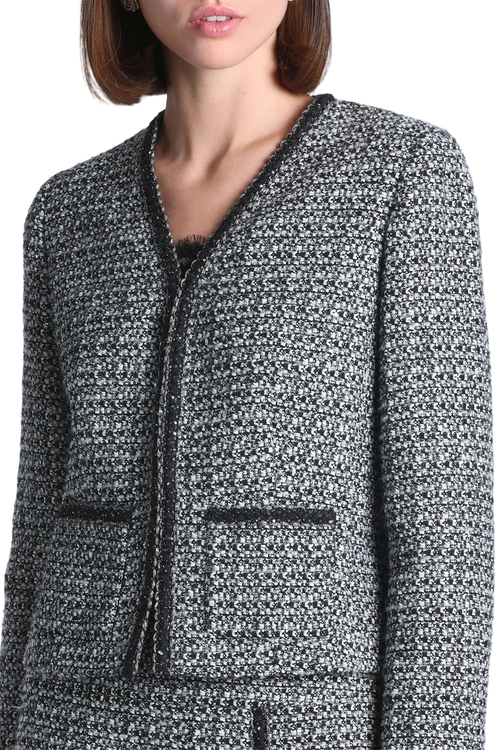 Black and cream speckled tweed jacket with V-neck, black trim, and two faux flap pockets.