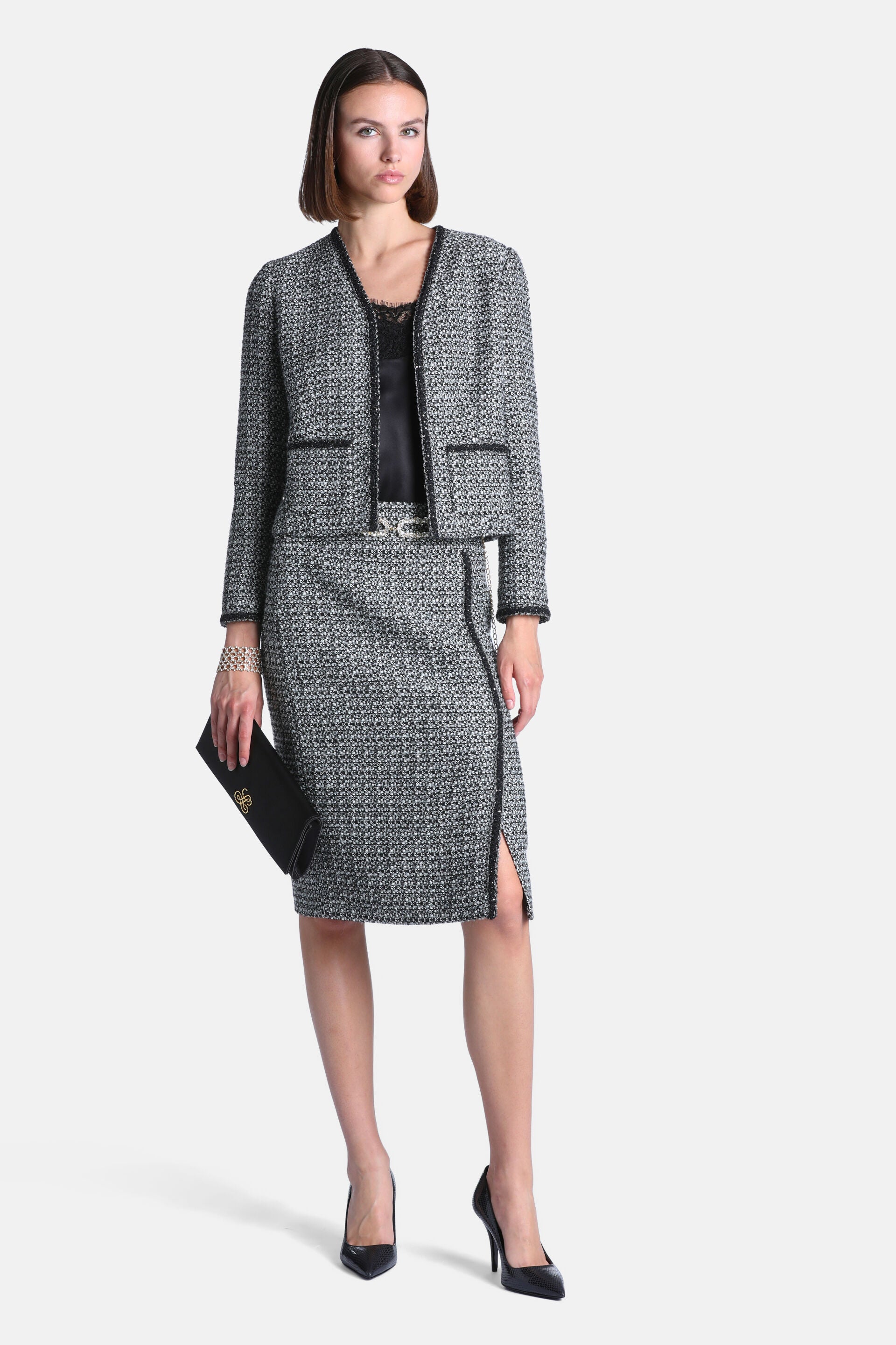 Black and cream tweed jacket with a V-neck, black trim along the edges, and two front patch pockets.