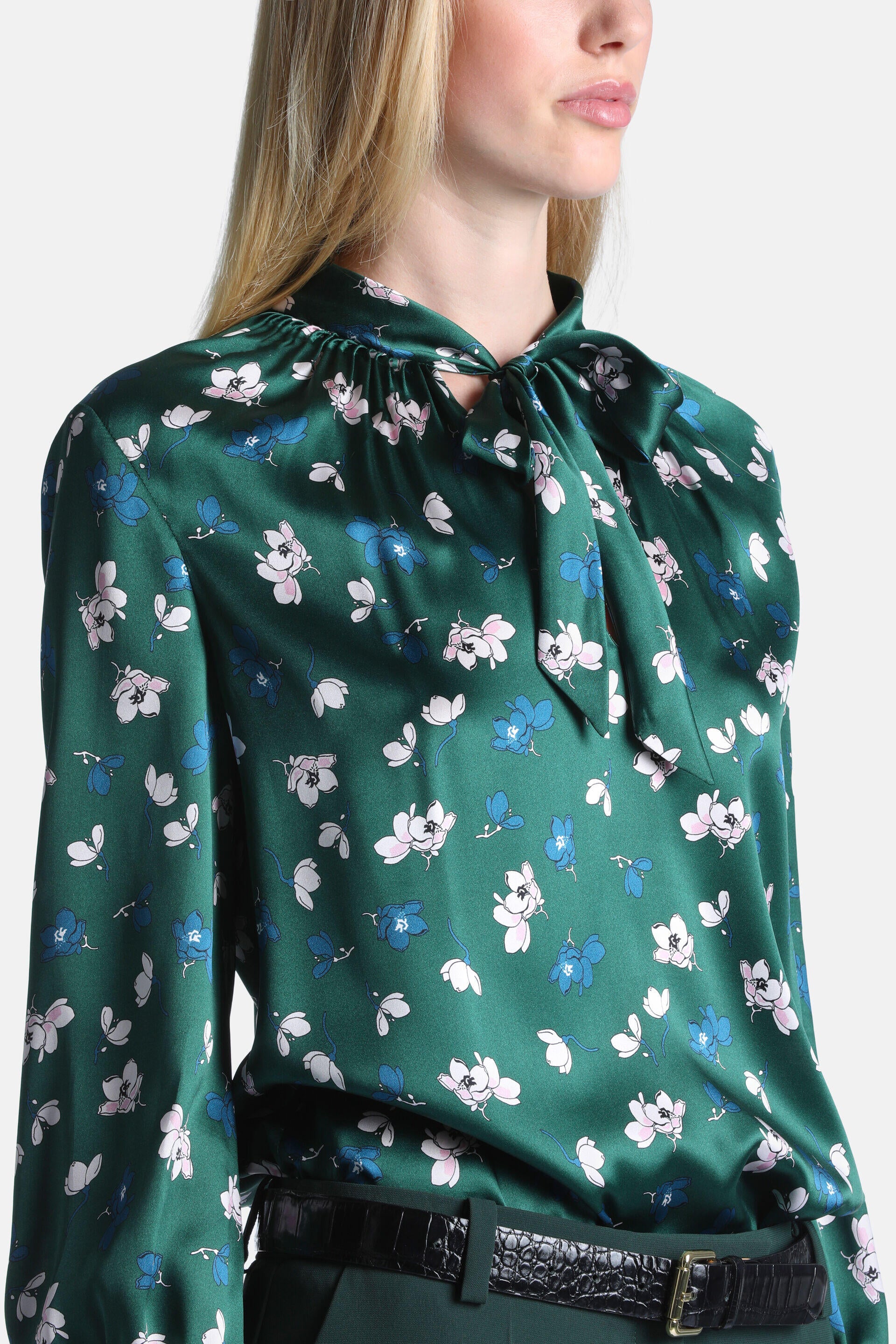 Green satin floral shirt with white and blue flowers, a gathered high neck, and a tie-bow detail.
