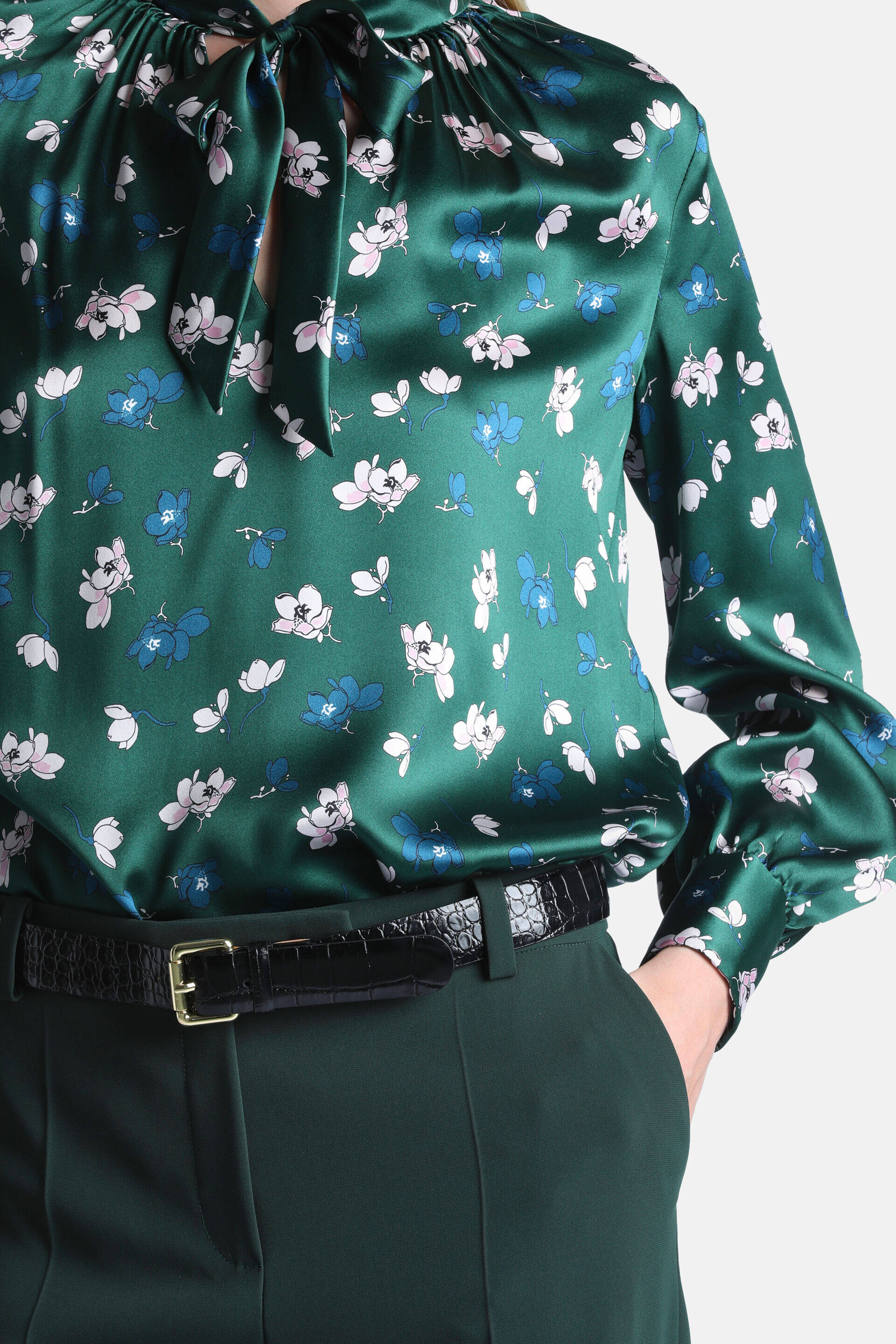 Green satin-look shirt with pink and blue floral print, a high tie-bow neckline, and gathered long sleeves.