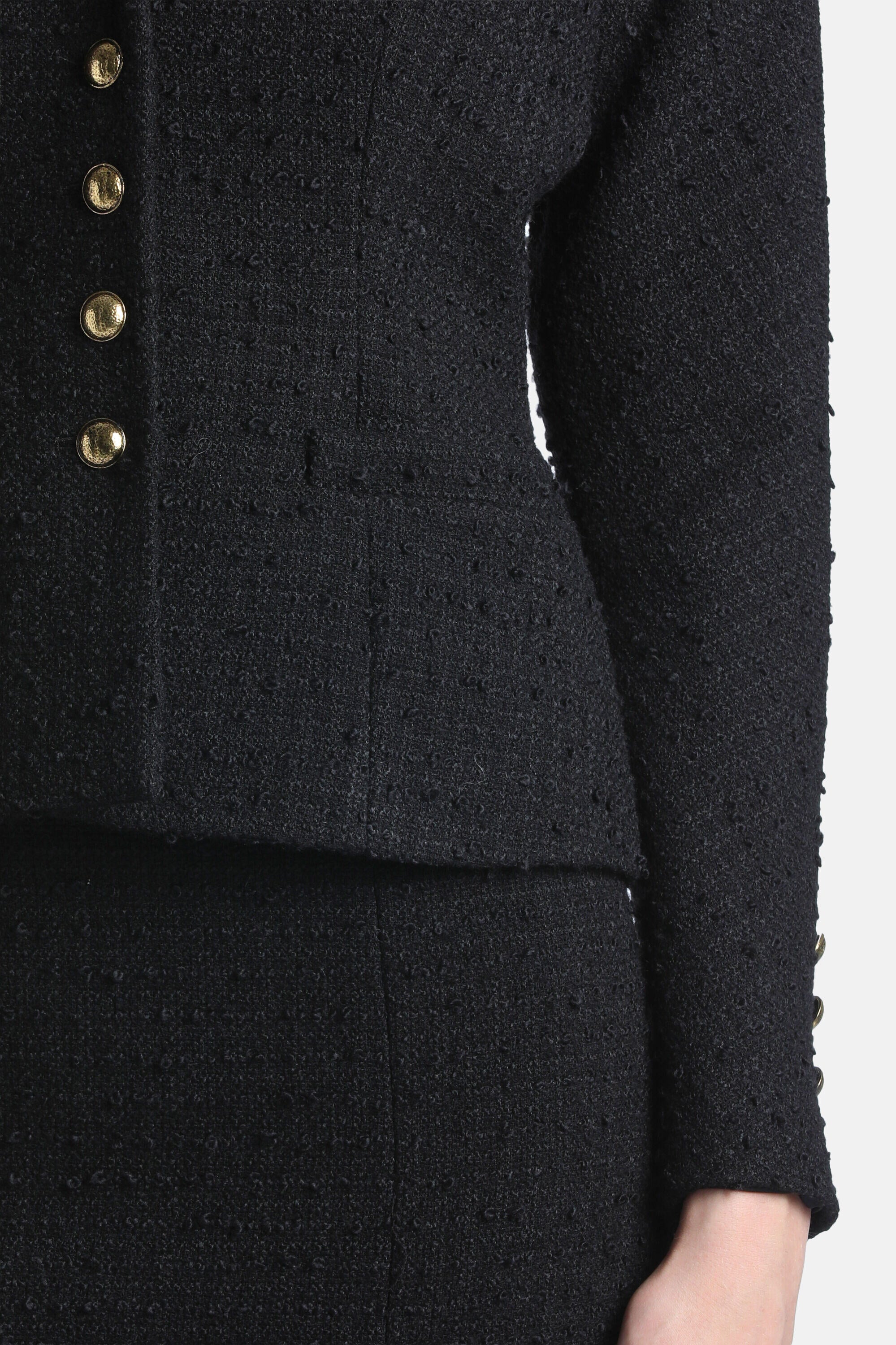 Black textured jacket with four gold-toned buttons on the front and three gold-toned buttons on the right sleeve cuff.