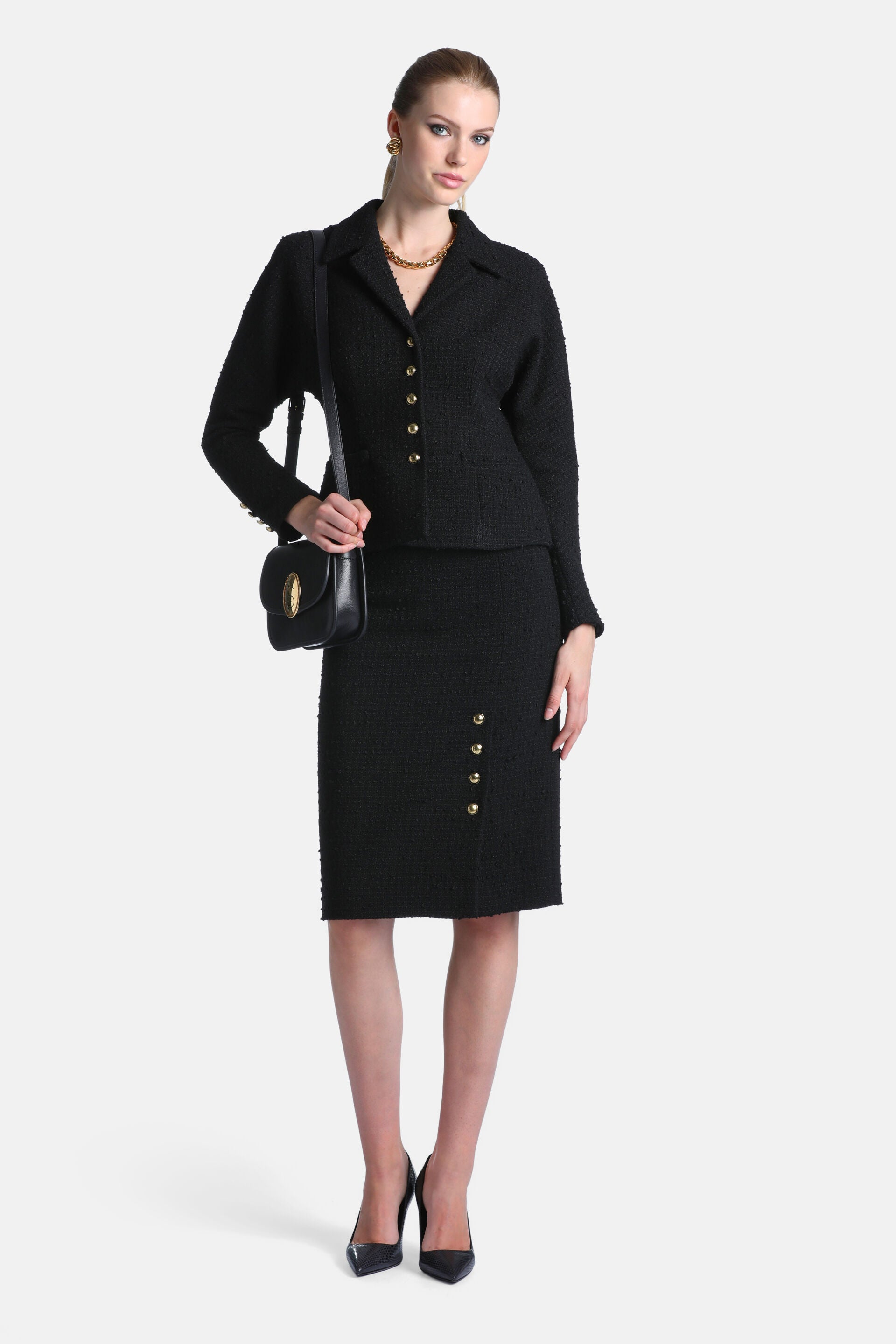 Black textured jacket with a pointed collar, four gold-toned buttons down the front, and one gold-toned button on each cuff.