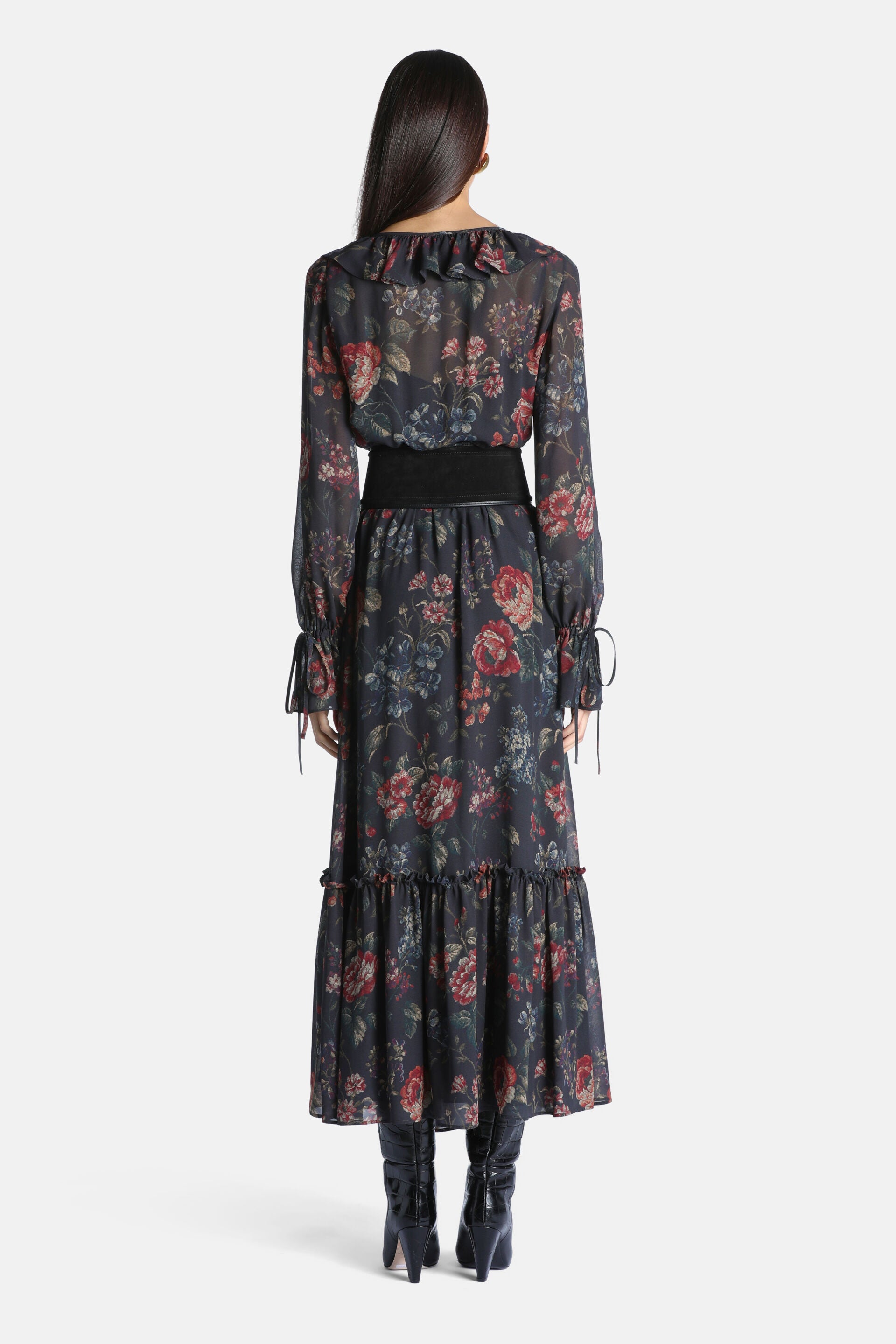 Long brown floral dress with red, pink, and blue flowers. Features a ruffled neckline, long sleeves with ties, a wide black w