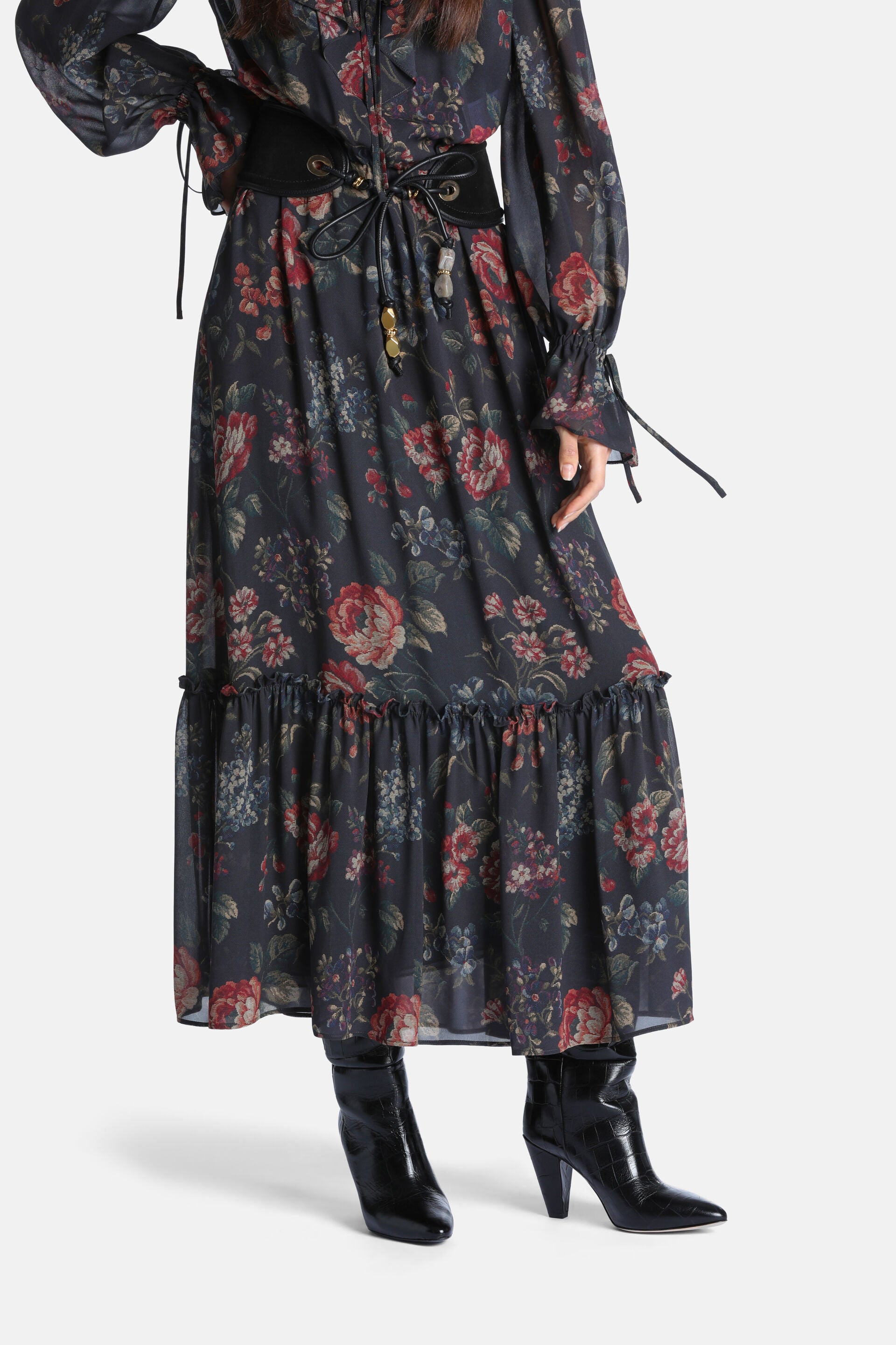 Dark brown floral maxi dress, long tie-cuff sleeves, tiered skirt. Black corset belt, gold-toned eyelets, beaded ties.