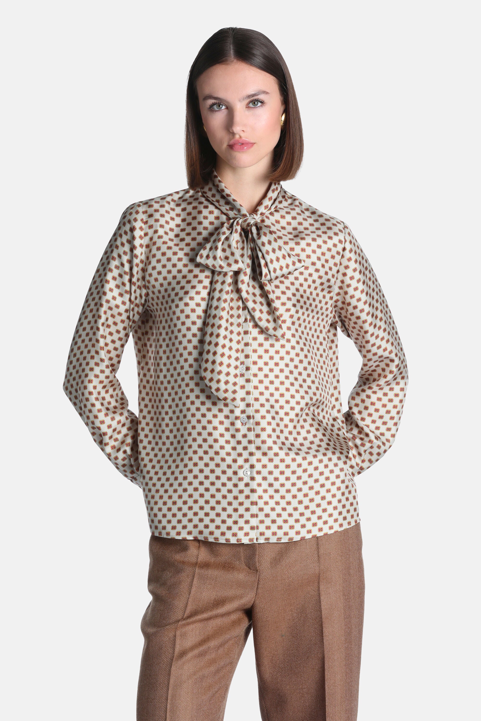 Cream silk shirt with small brown square pattern, long sleeves, and a pussy-bow tie at the neck. Button-front.