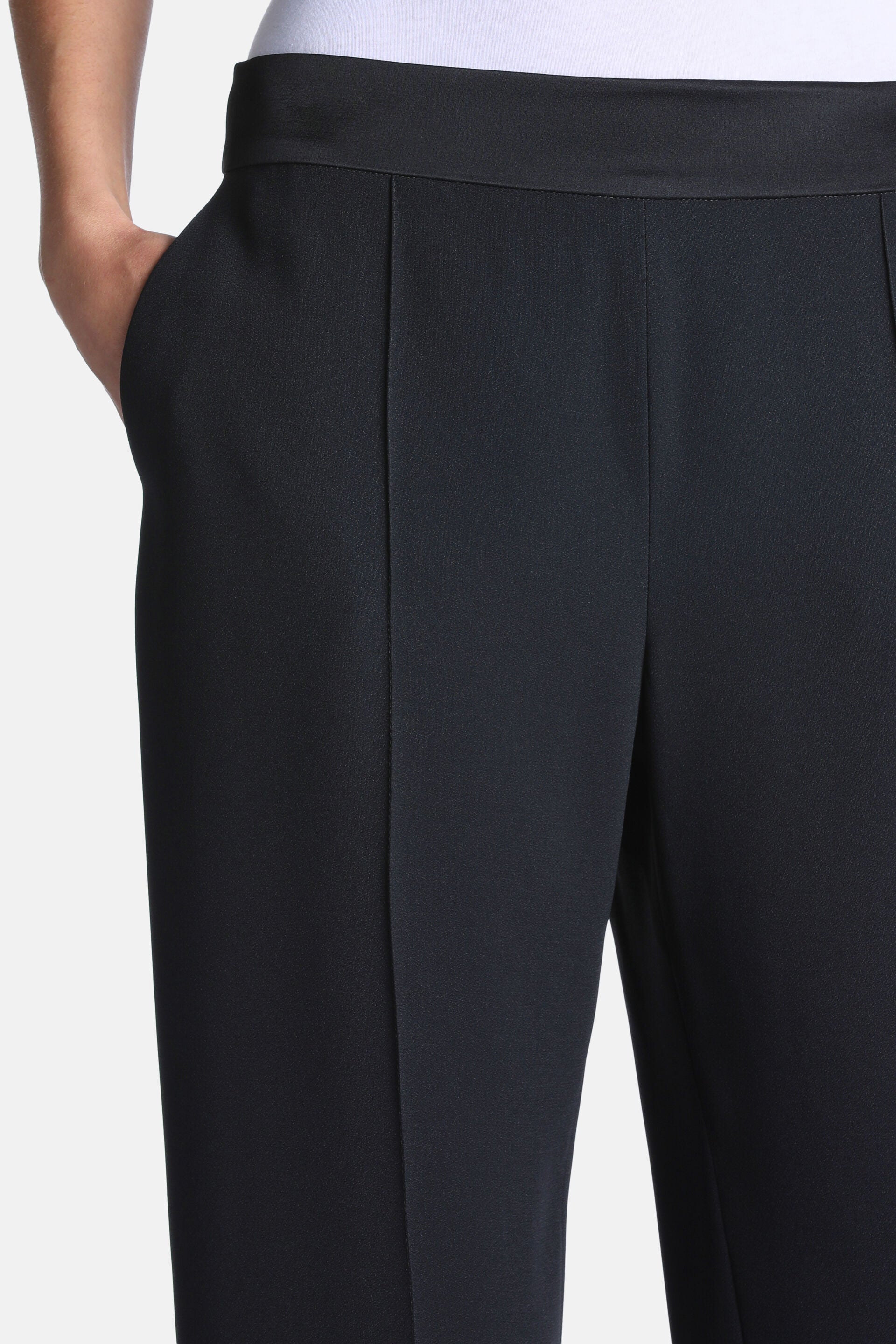 Black trousers with a flat front waistband, side pockets, and pressed creases down the front legs.