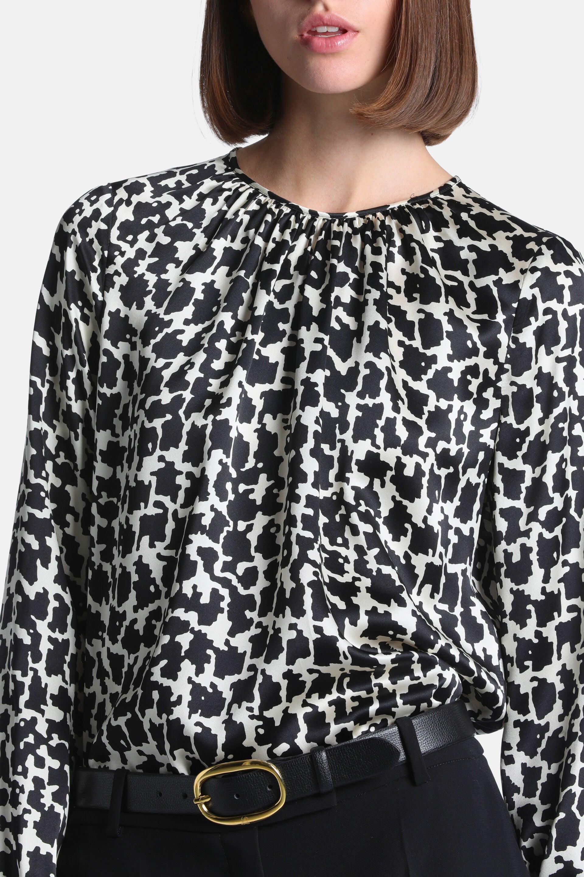 Black and cream abstract pattern long-sleeved shirt with a gathered round neckline, made of smooth, flowing fabric.