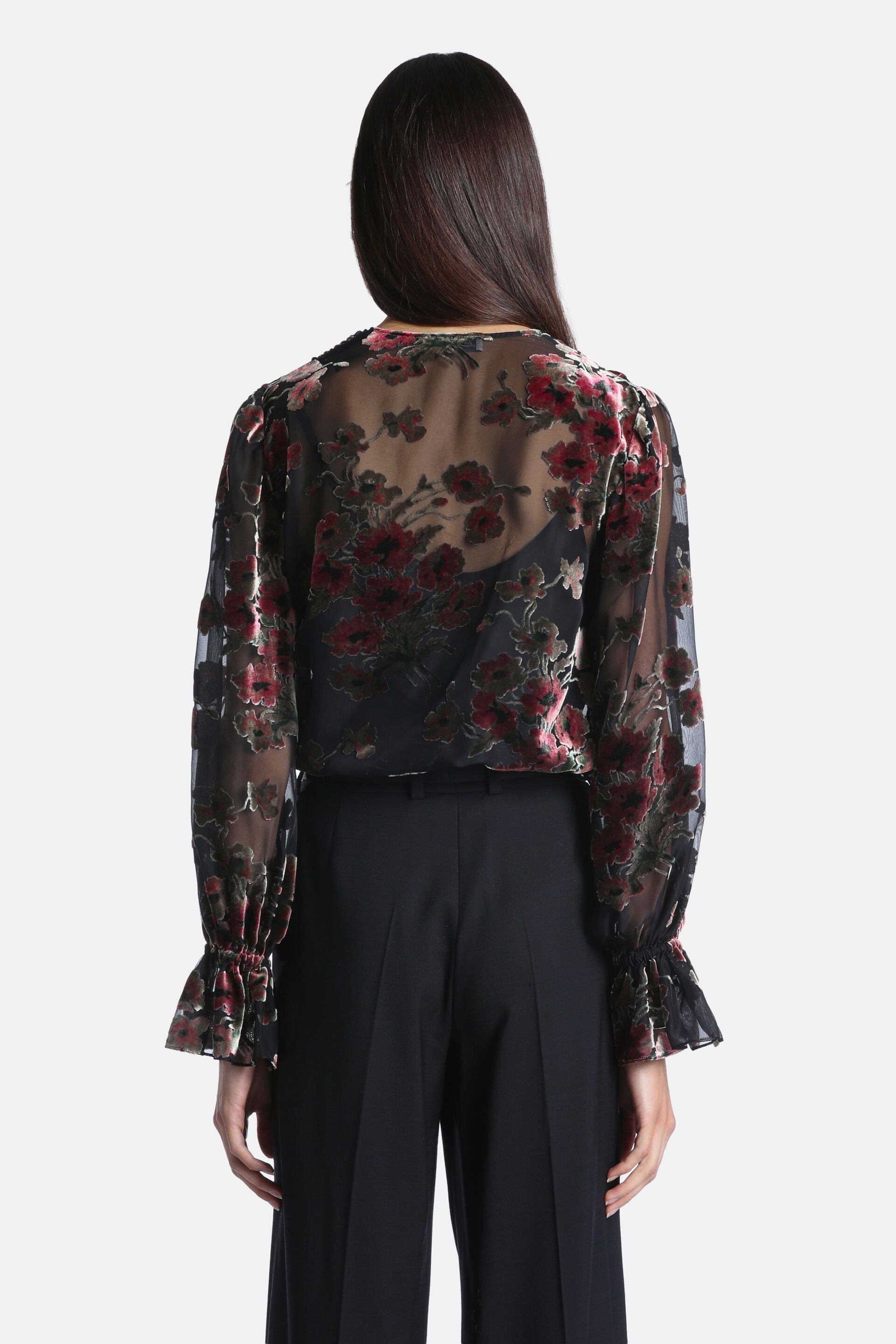 Sheer black blouse with velvet red and pink floral pattern, long sleeves with ruffled cuffs.