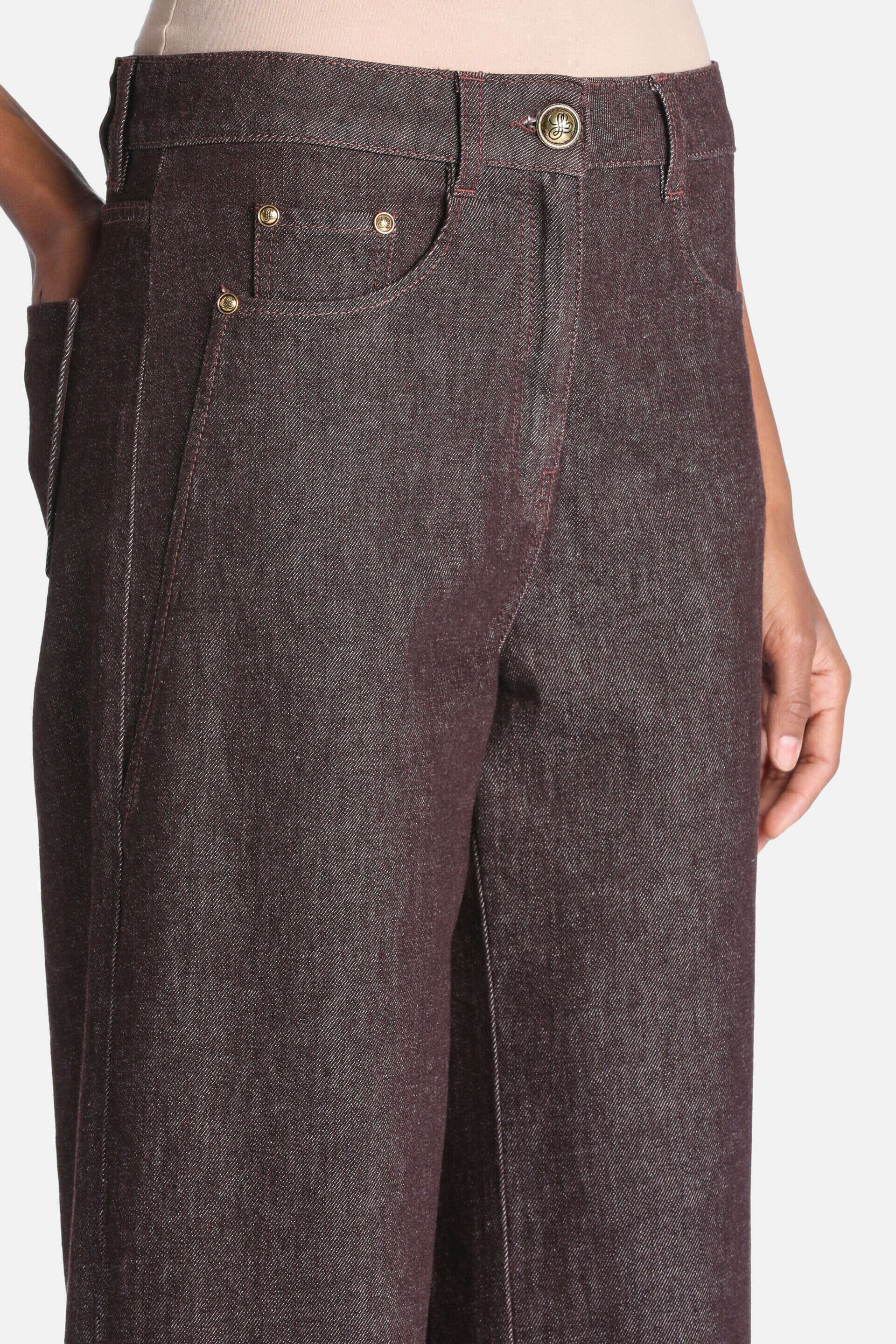 Dark brown denim trousers with gold-toned button, front pockets with gold-toned rivets, and reddish-brown stitching.