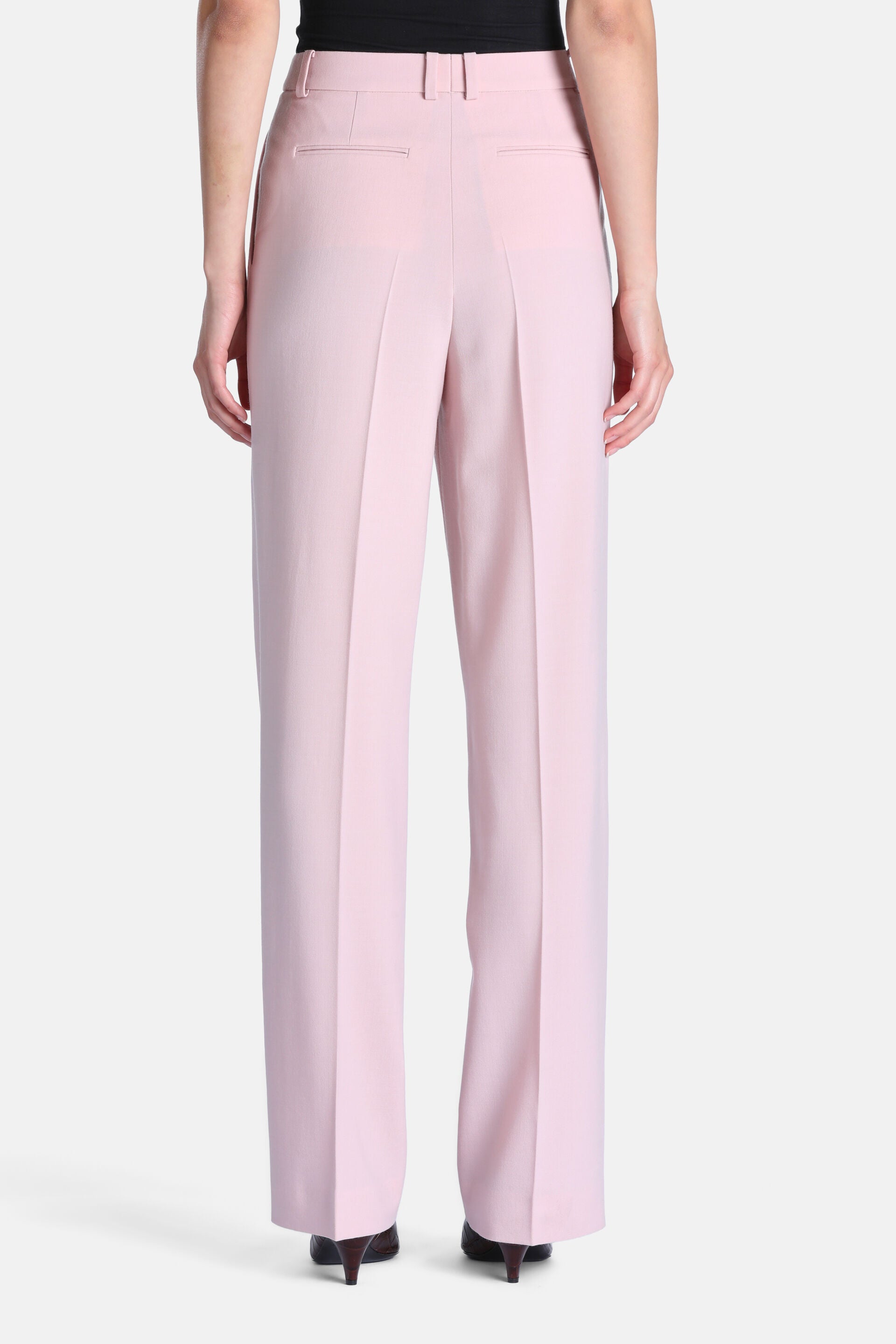 Pink wide-leg trousers with belt loops, two back welt pockets, and prominent vertical creases down each leg.