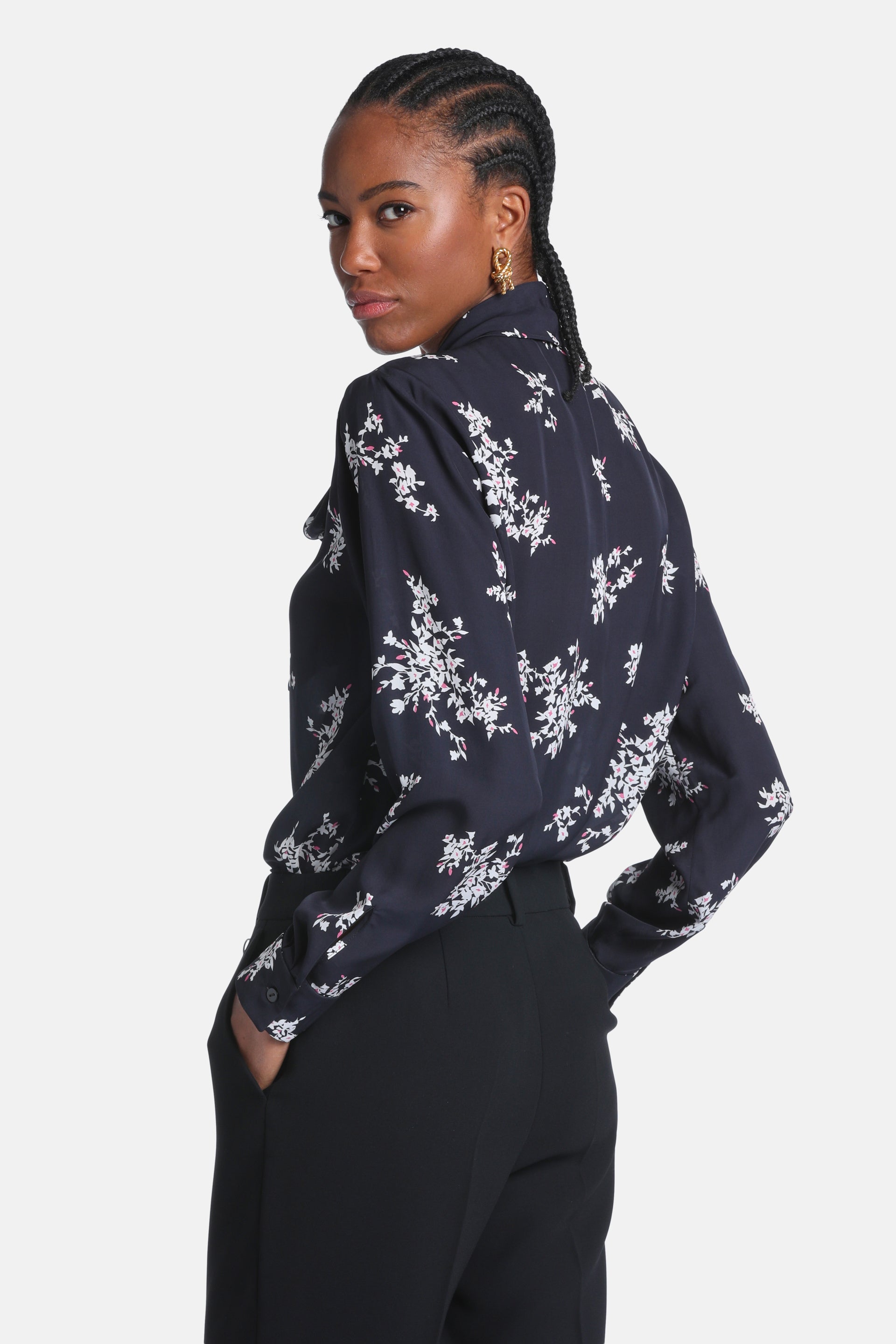 Black long-sleeved shirt with an all-over cream and pink floral print, pointed collar, and buttoned cuffs.