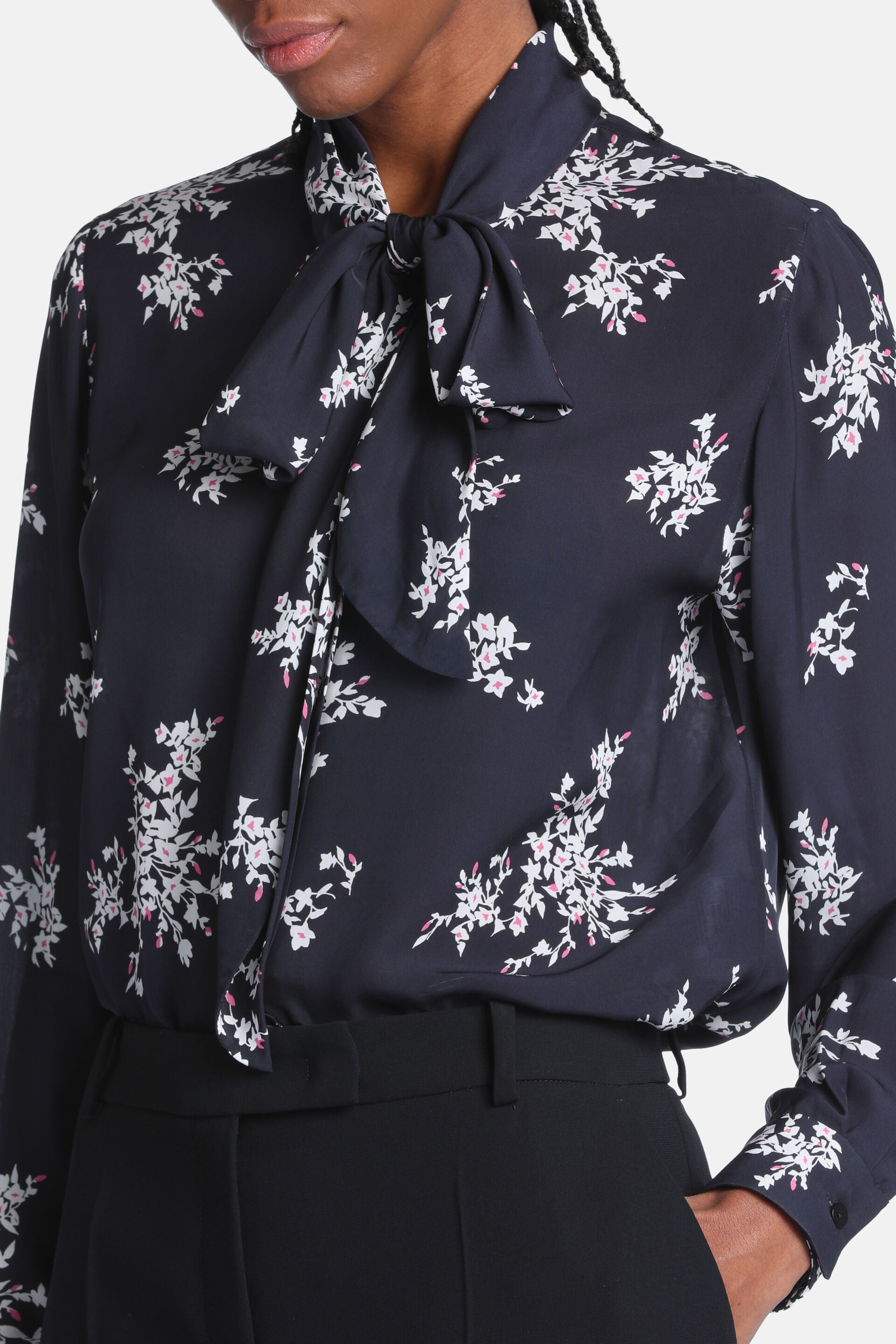 Black floral shirt with cream and pink flowers, a pussy-bow tie at the neck, and long sleeves with buttoned cuffs.