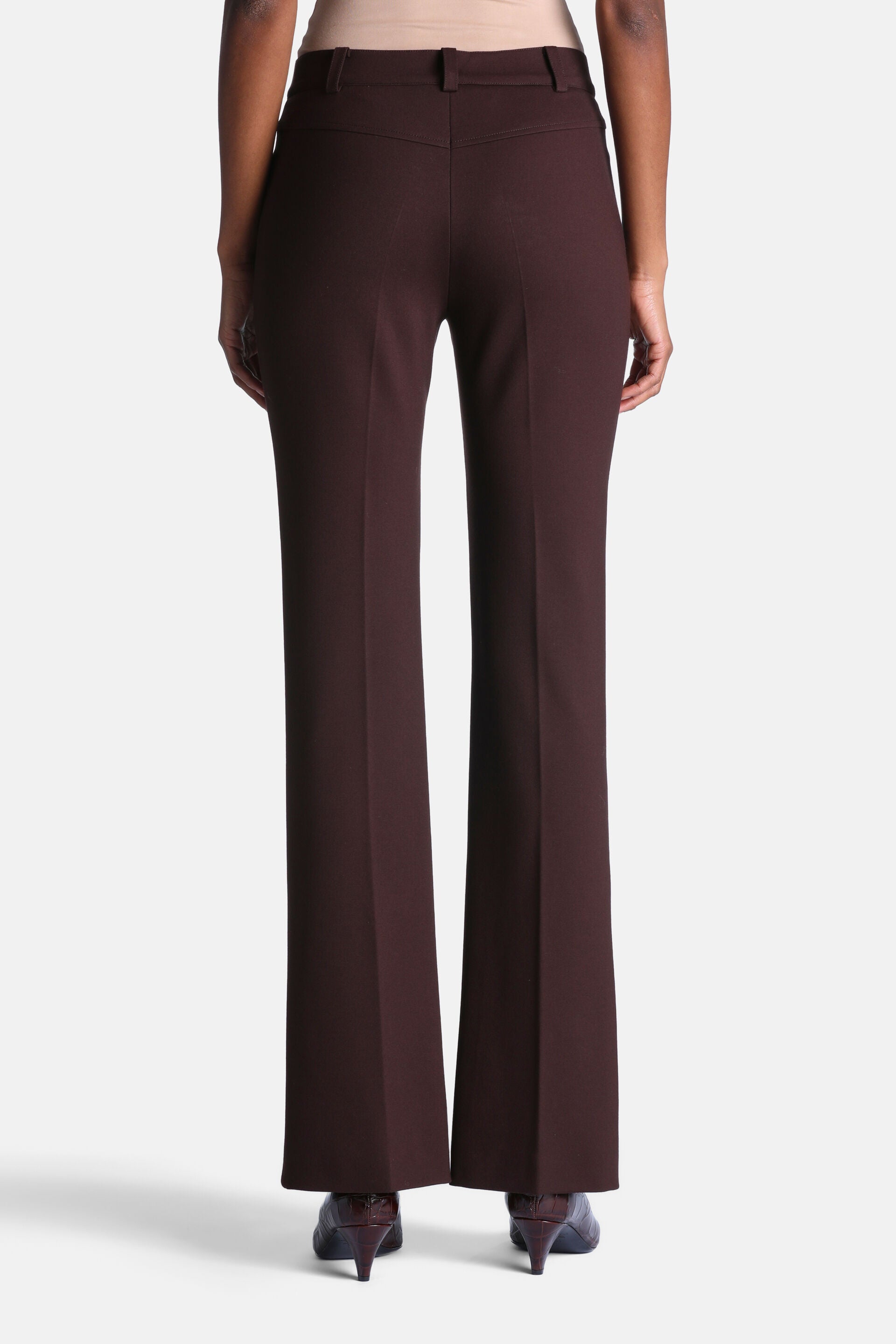 Brown high-waisted trousers with a V-shaped back yoke, belt loops, and flared legs with vertical creases.