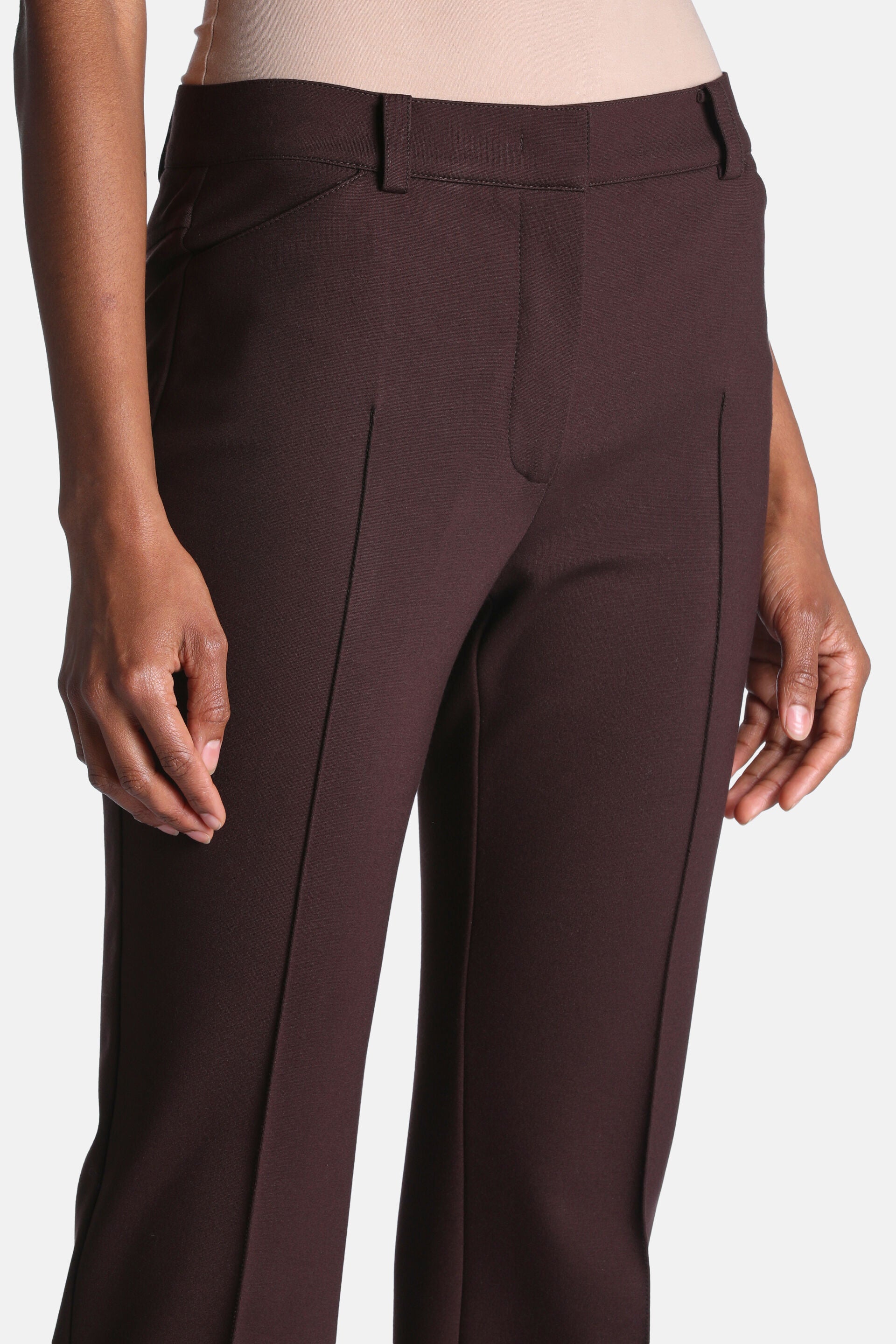 Dark brown tailored trousers with a smooth fabric, front fly closure, belt loops, and vertical front leg seams.