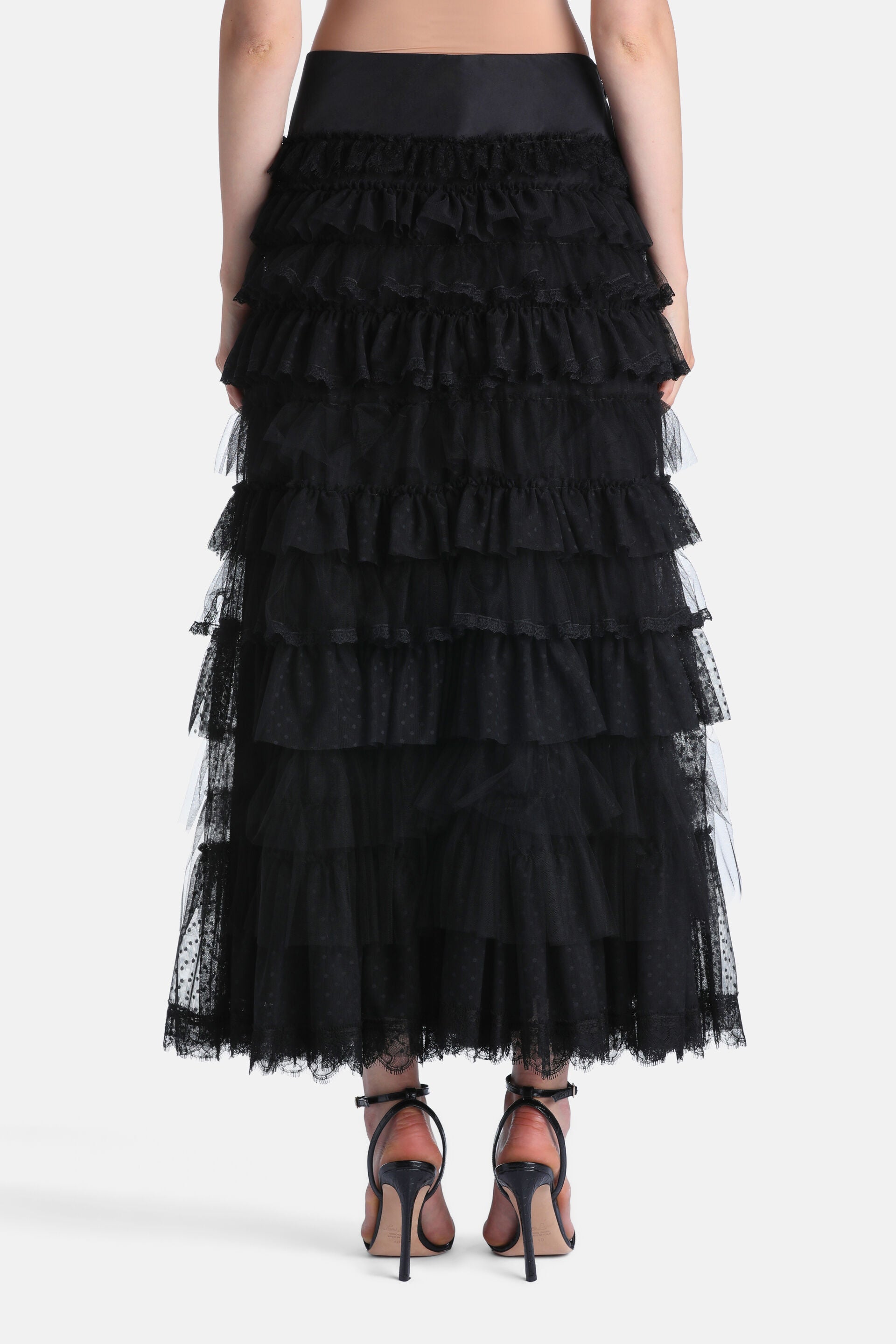 Black tiered maxi skirt with a smooth waistband and multiple ruffled layers of sheer, polka-dotted fabric, finished with lace