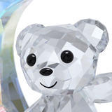 Faceted clear crystal bear figurine with black eyes, nose, and a smile, next to a blue-toned iridescent crystal crescent moon