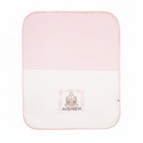White and pink knit baby blanket with a cartoon bear graphic and Aigner logo on the lower white section.