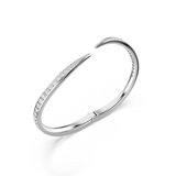 Silver-toned open bangle. One end is a straight, pointed bar encrusted with clear stones. The other end is a curved bar with