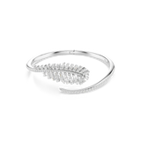 Silver-toned open bangle bracelet with a large feather-shaped cluster of clear baguette and round crystals on one end, and a