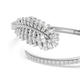 Silver-toned bangle with a large leaf-like cluster of clear baguette and round crystals on one end, and a curved band with ro