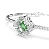 Silver-toned bangle with a clover centerpiece featuring a green stone and clear stones. The band is stone-encrusted with a lo