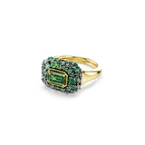 Gold-toned ring with a rectangular emerald-cut green stone, bordered by smaller green and tiny dark green stones.