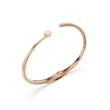 Rose gold-toned open bangle with a single large clear crystal on one end and a row of small clear crystals on the other.